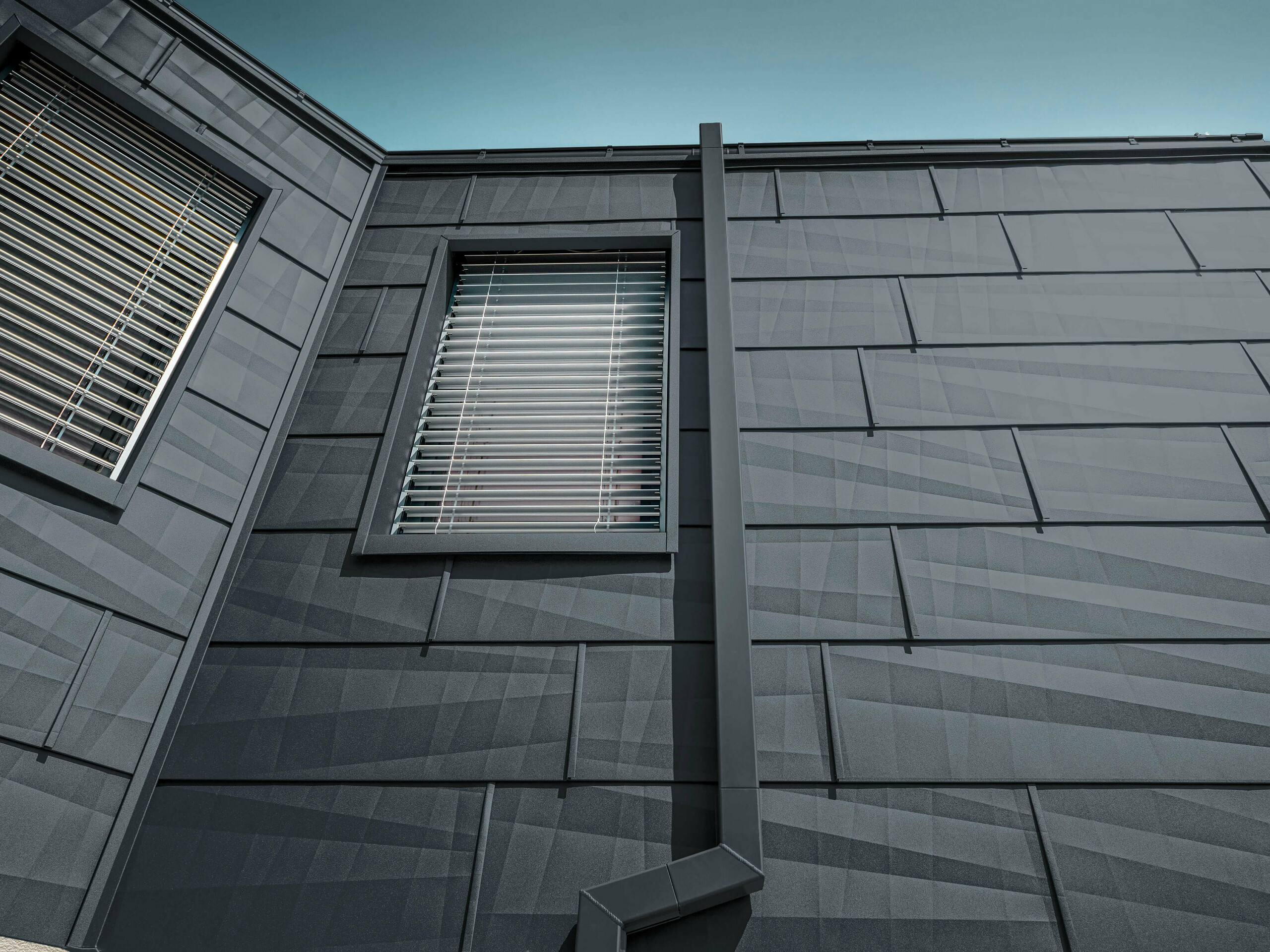 Fasade kledd med PREFA fasadepanel FX.12 i antrasitt, aluminiumspanel på fasaden med firkantede avløpsrør og firkantrør i antrasitt fra PREFA.