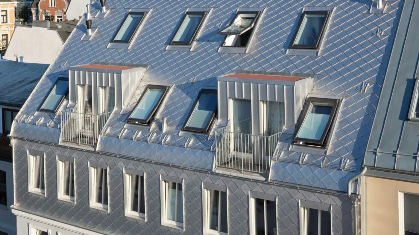 Blankt aluminiums-overlappstak med loftsutbygging og mange overlysvinduer