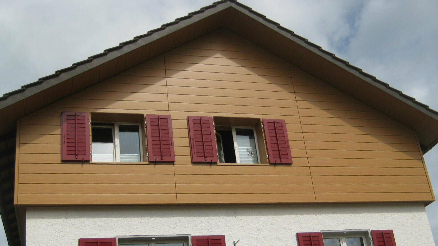 Husfasade med treutseende med PREFA Sidings lagt horisontalt, vindu med røde skodder