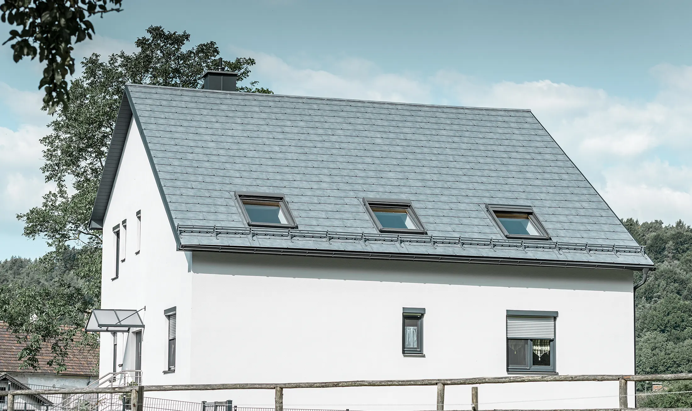 Saltaket på en klassisk enebolig er kledd med den nye PREFA takplate R.16 i steingrå. På takflaten er det lagt inn tre takvinduer, og det er montert snøfangere. Fasaden er ganske enkelt holdt i hvitt.