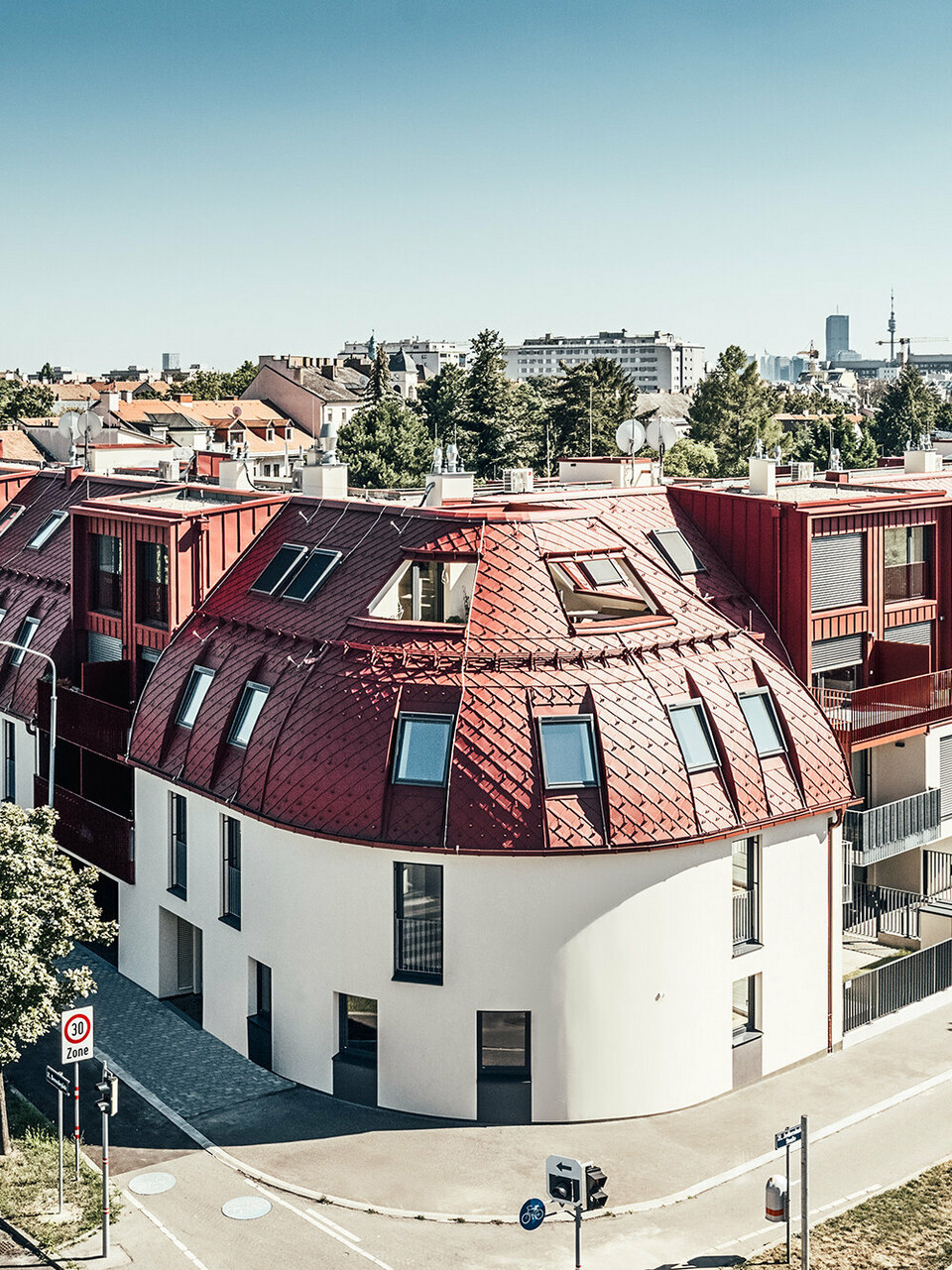 Straßenansicht auf die Wohnanlage Schöneck 13 und die abgerundete Dachlandschaft, entworfen vom Architekturbüro schneider+schumacher.