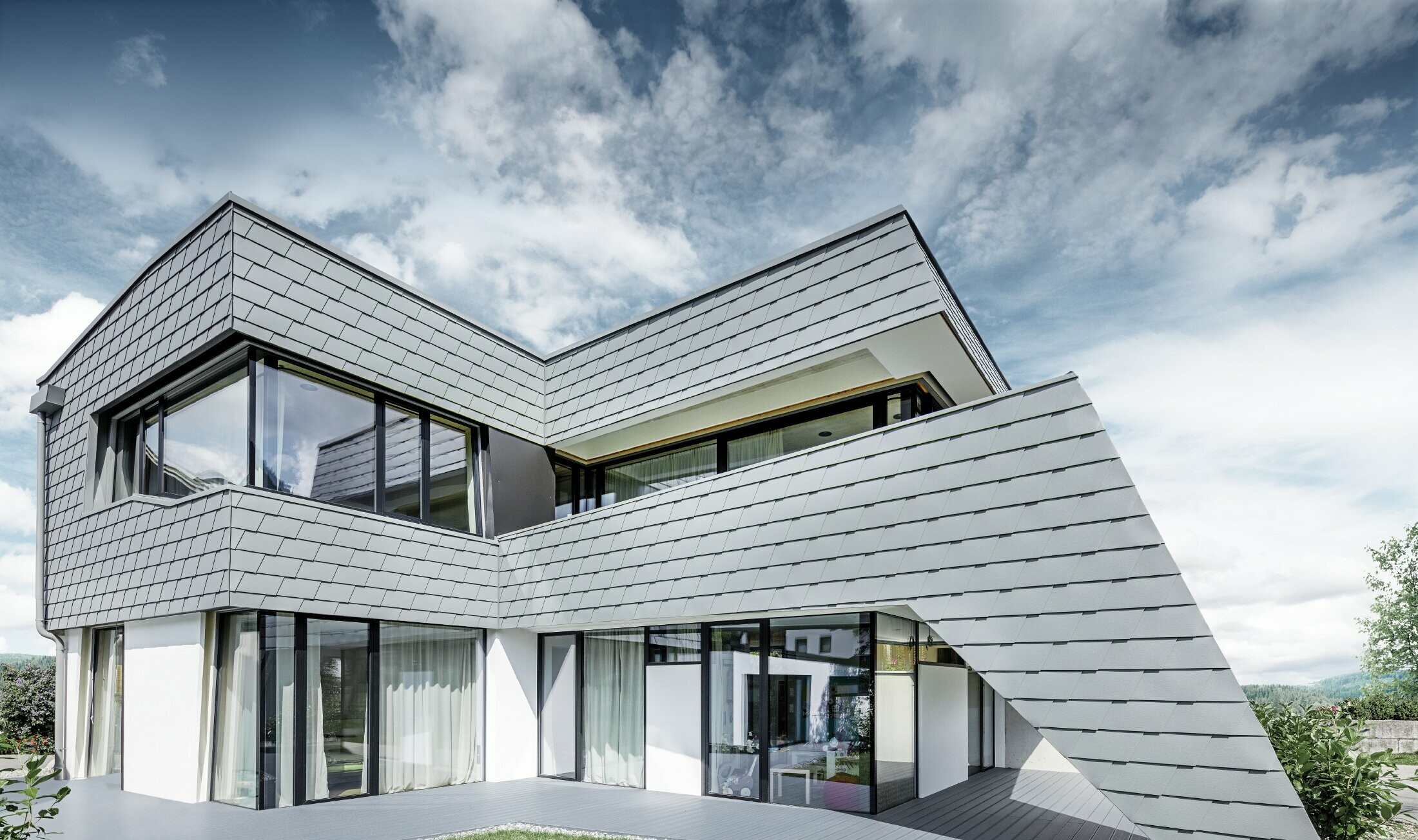 Moderne enebolig med flatt tak, store vindusflater og singelfasade i lys grå aluminium fra PREFA.