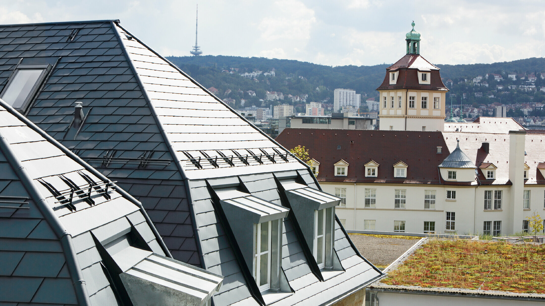 Gammelt rekkehus i Stuttgart med skjevt tak og mange arkvinduer, dekket med aluminiumsshingel fra PREFA i P.10 antrasitt