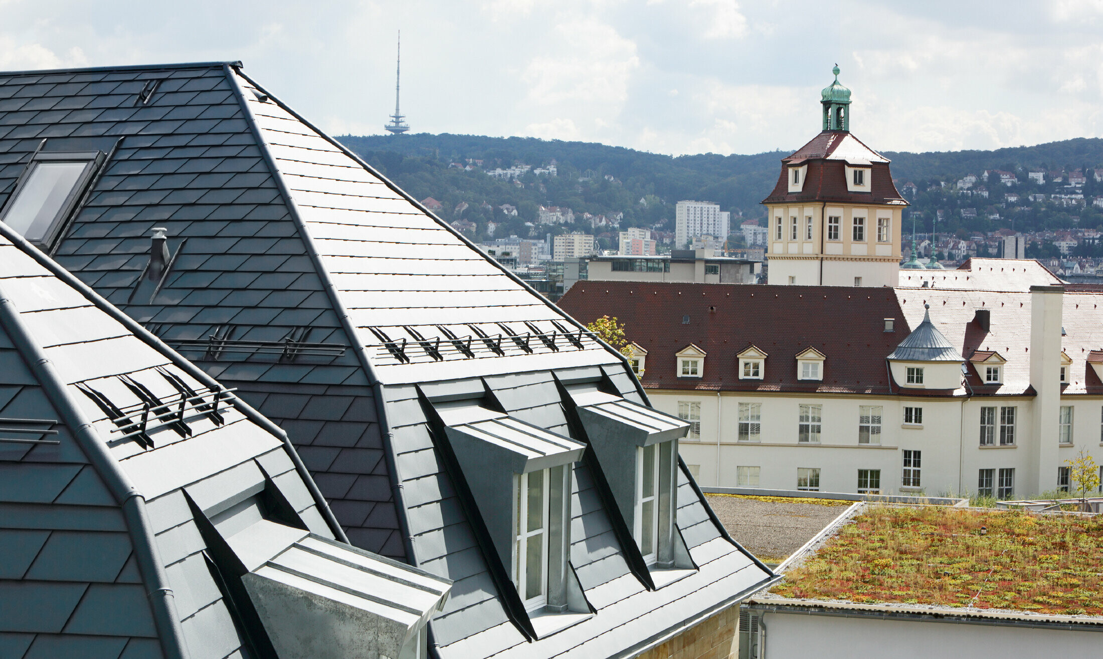 Gammelt rekkehus i Stuttgart med skjevt tak og mange arkvinduer, dekket med aluminiumsshingel fra PREFA i P.10 antrasitt