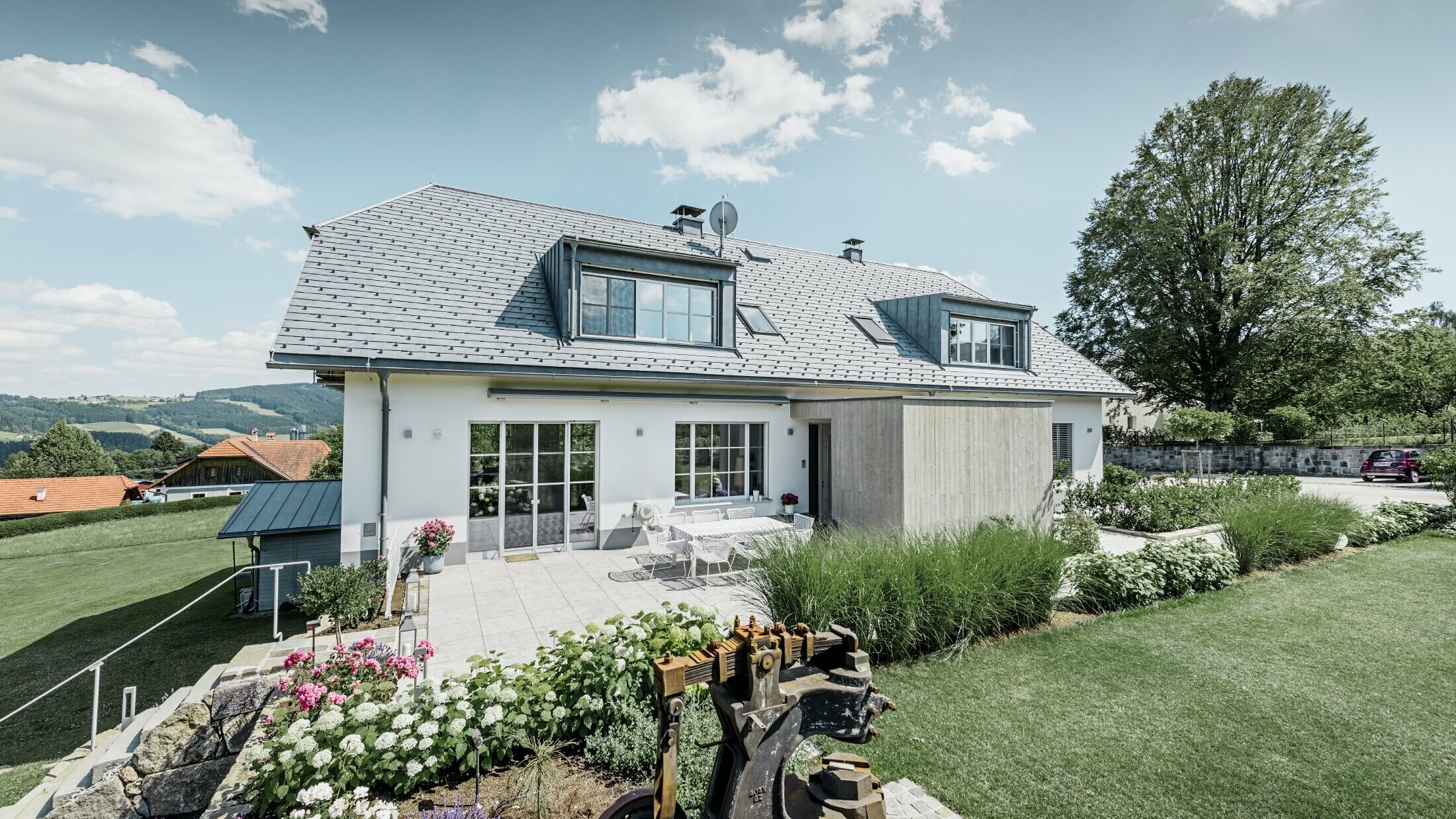 Klassisk enebolig med halvvalmtak – Huset med takrenovering med PREFA-takshingel i steingrå med vakkert opparbeidet hage og romslig terrasse.