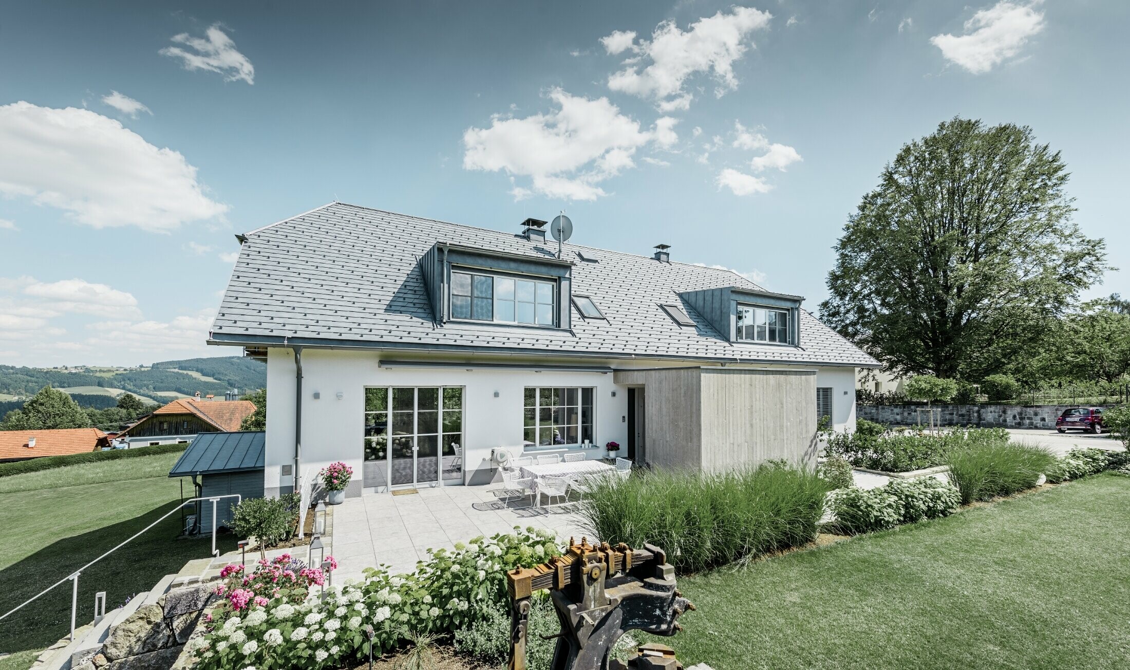 Klassisk enebolig med halvvalmtak – Huset med takrenovering med PREFA-takshingel i steingrå med vakkert opparbeidet hage og romslig terrasse.