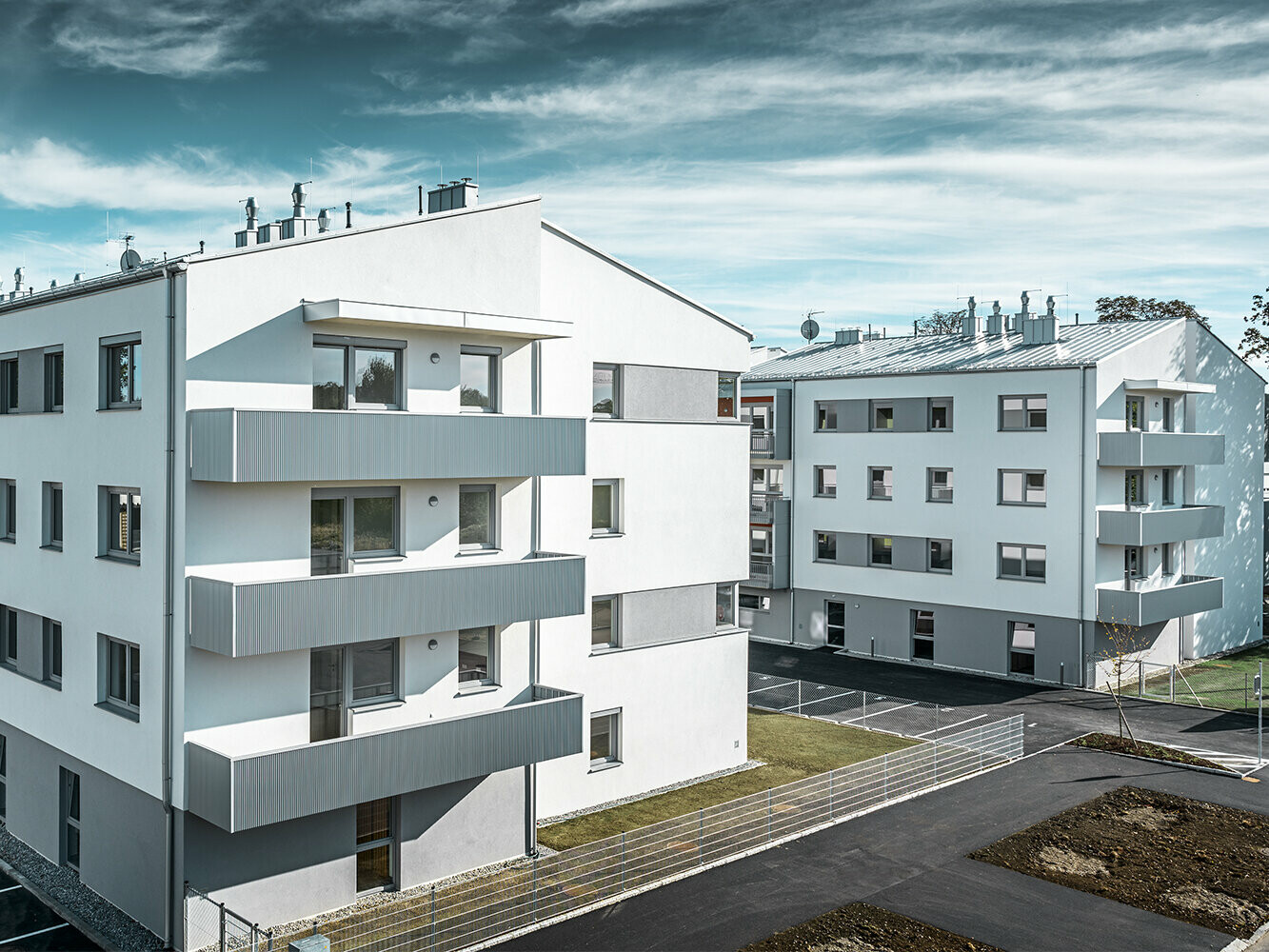 Moderne boligkompleks med hvit fasade og balkonger med PREFA sikksakkprofil i sølvmetallic