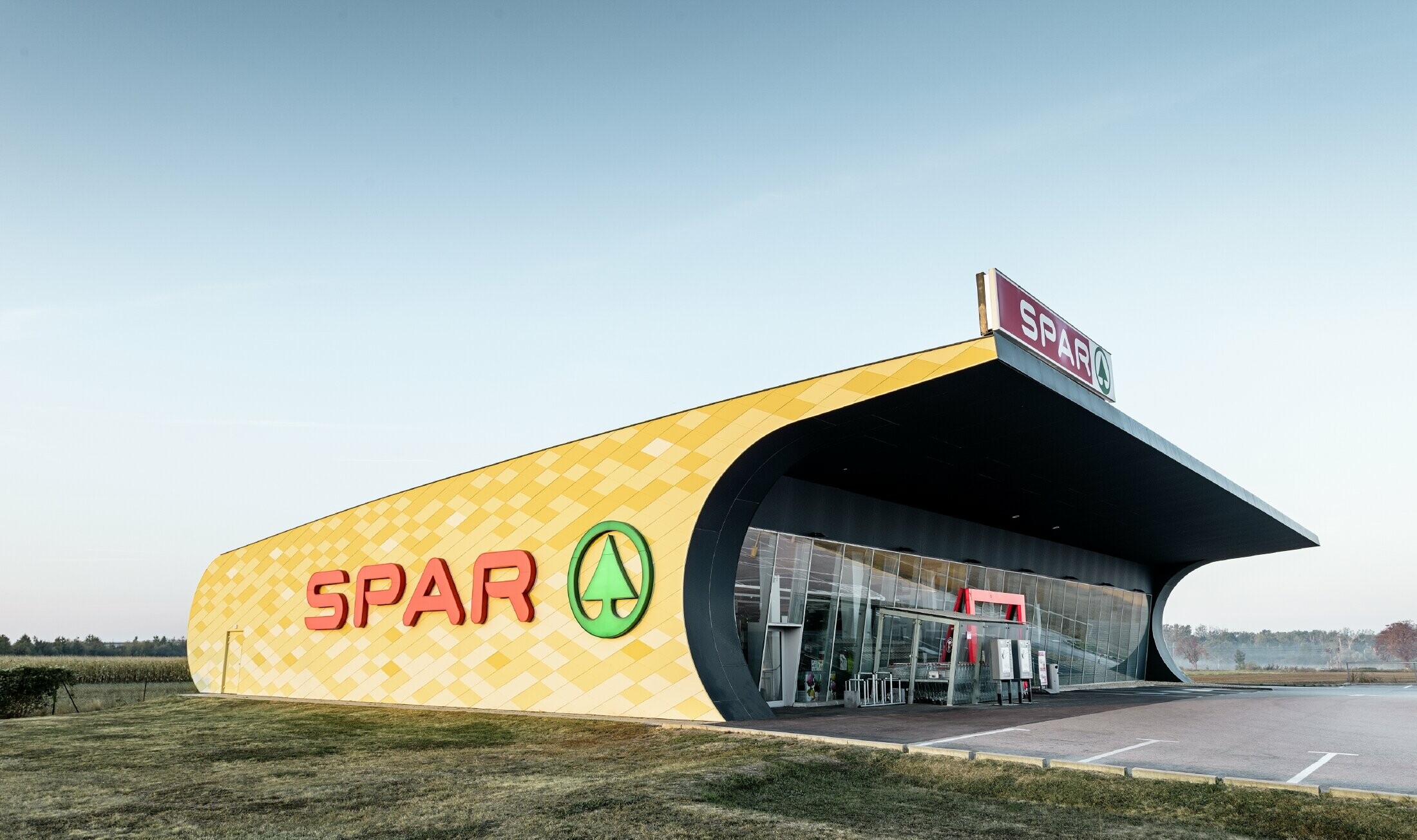 Spar-filial med aluminiumsfasade i gul-oransje rutermønster og Spar-logo