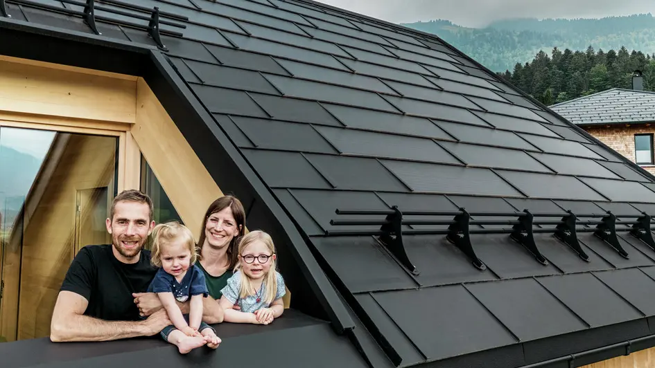 De to byggherrene nyter utsikten sammen med barna fra loggiaen i sitt nybygde hus, som er utstyrt med stilfulle PREFA-solcelle takplater i P.10 svart.