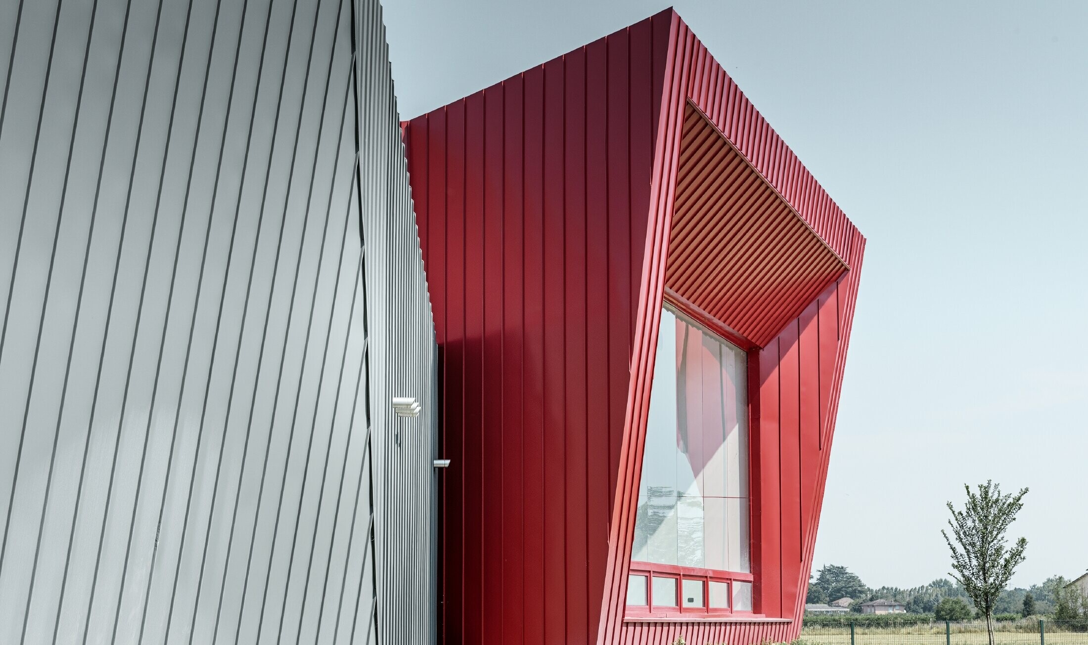 moderne treningssenter i Dieci i Montecchio Emilia i Italia, med tribune med aluminiumsfasade med Prefalz i lysegrått og Falzonal i karminrødt 
