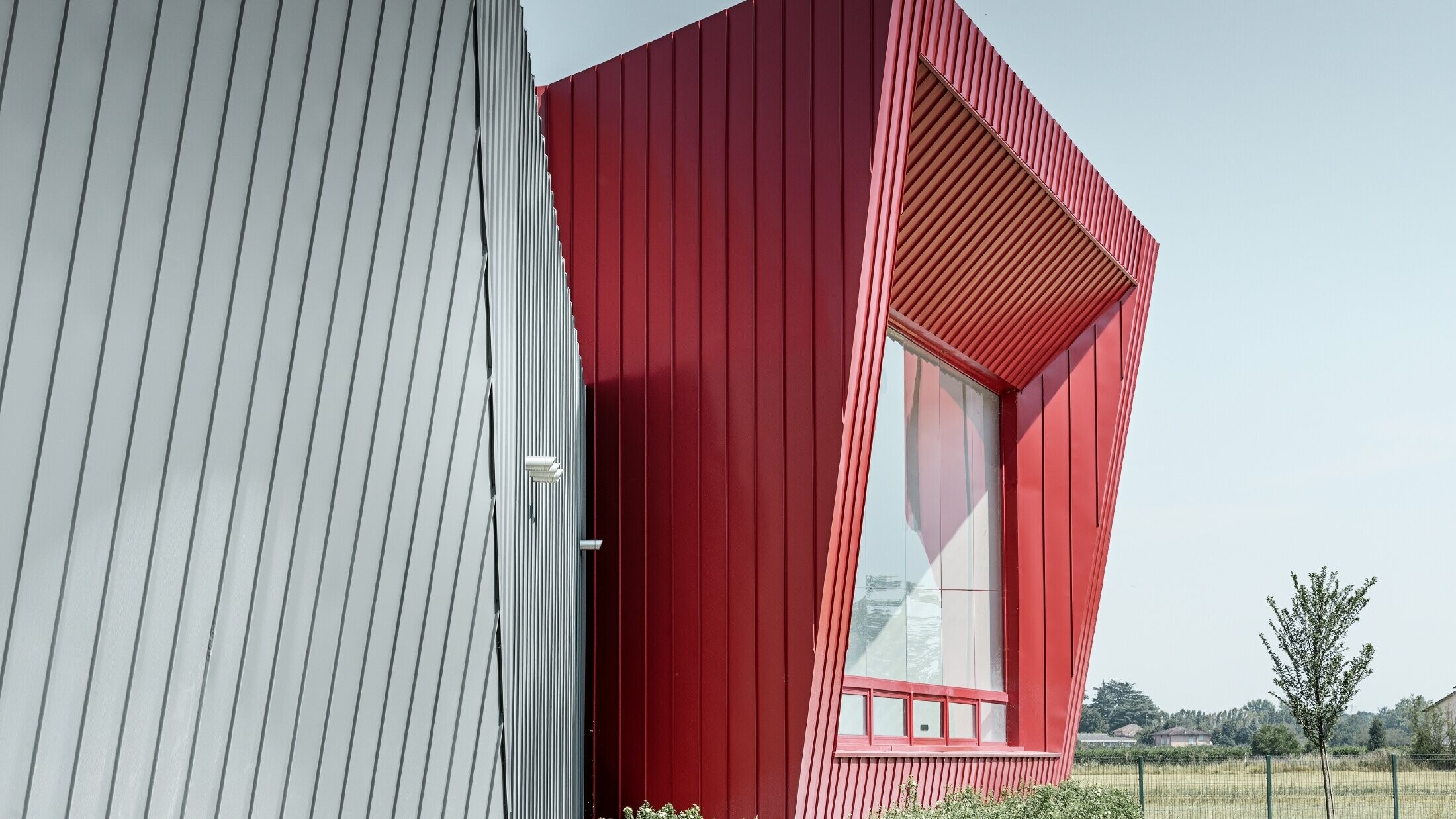 moderne treningssenter i Dieci i Montecchio Emilia i Italia, med tribune med aluminiumsfasade med Prefalz i lysegrått og Falzonal i karminrødt 