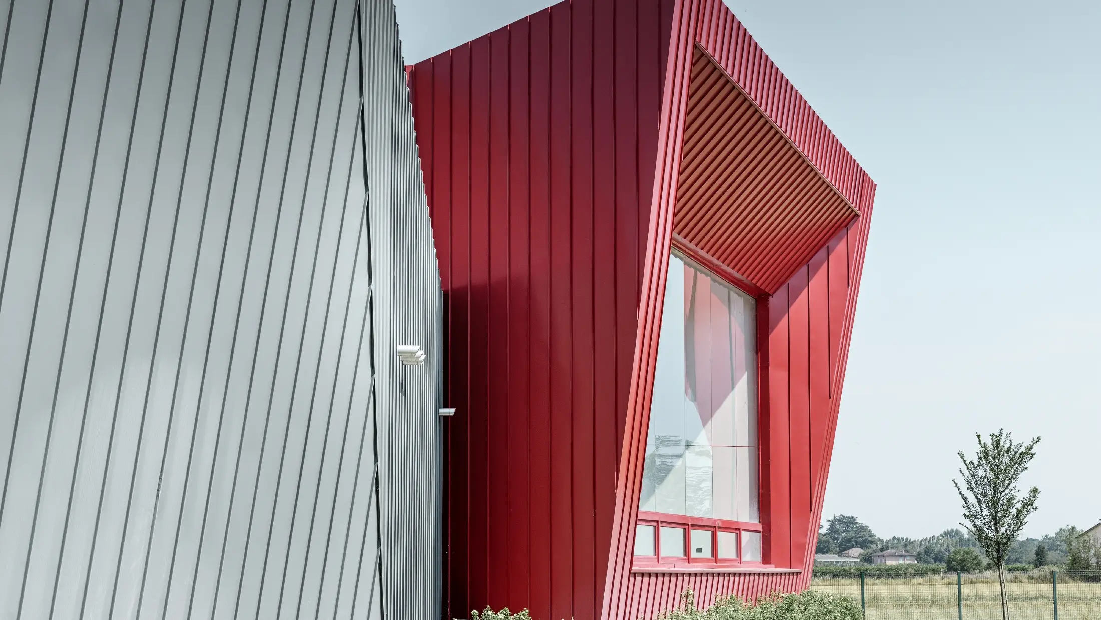 moderne treningssenter i Dieci i Montecchio Emilia i Italia, med tribune med aluminiumsfasade med Prefalz i lysegrått og Falzonal i karminrødt 