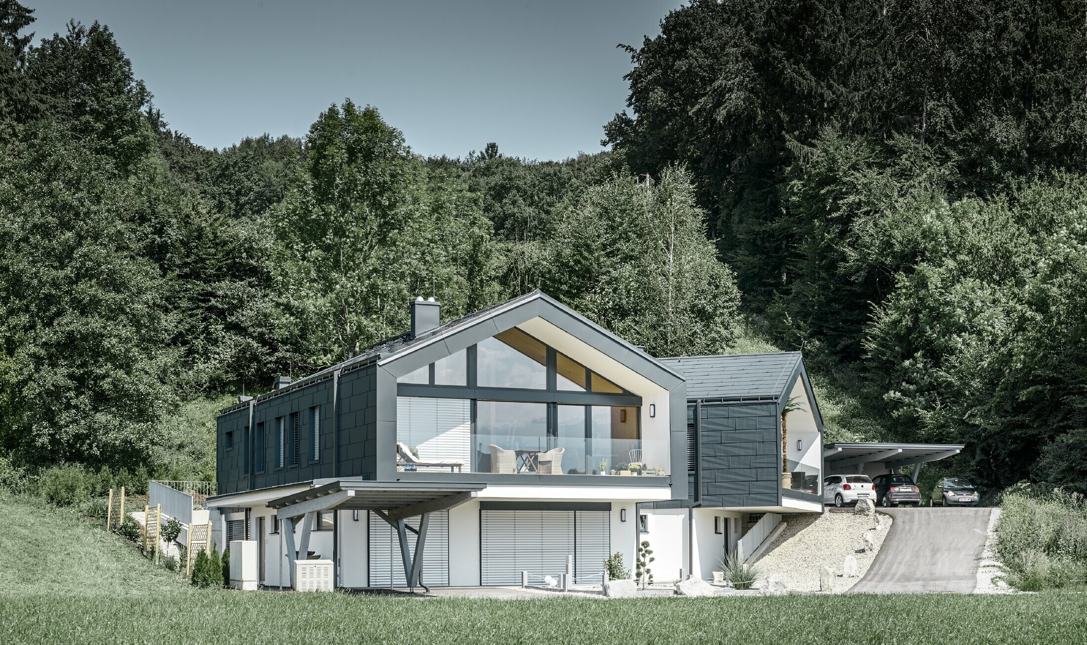 Modernes Mehrfamilienhaust mit einer großen Fensterfront, Dach und Fassade wurden mit dem Dach- und Fassadenpaneel FX.12 in anthrazit von PREFA bekleidet