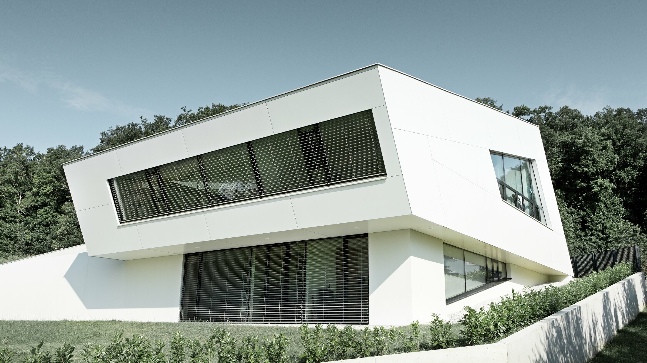 Meget moderne enebolig med hvit PREFA komposittplatefasade og store vinduer