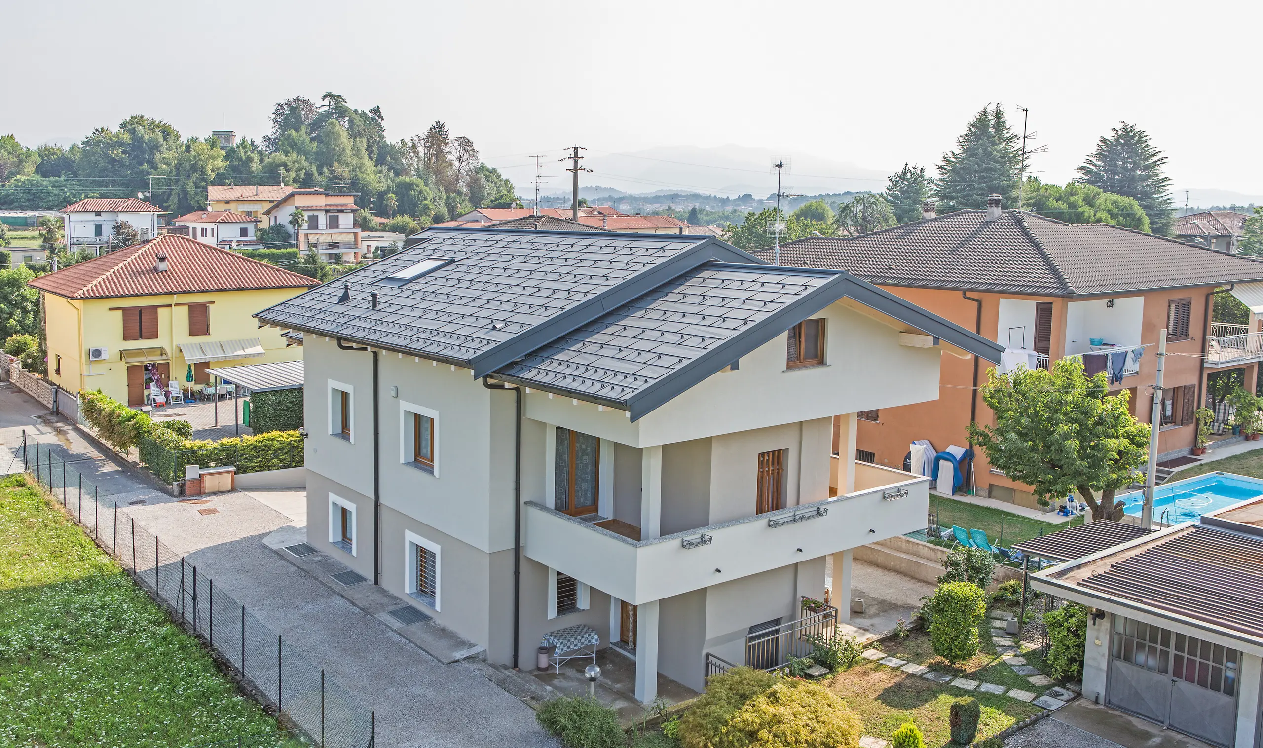 Modernes Einfamilienhaus in Beregazzo, Italien, mit markantem Satteldach aus PREFA Dachpaneelen FX.12 in P.10 Anthrazit. Die unregelmäßig gekanteten Aluminium-Paneele erzeugen ein lebendiges Licht- und Schattenspiel und setzen einen starken architektonischen Akzent. Das langlebige PREFA Aluminiumdach verbindet zeitgemäßes Design mit hoher Widerstandsfähigkeit und zuverlässigem Schutz vor Witterungseinflüssen.