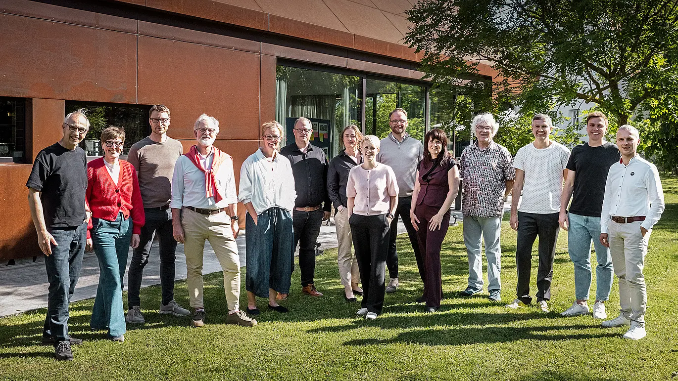 Gruppe von Architektur-Experten vor einer modernen Winzerresidenz im Seewinkel. Das Bild wurde inszeniert vor einem markanten, rostfarben schimmernden Gebäude mit klaren Linien und großzügigen Glasflächen. Die metallische Oberfläche reflektiert das Licht und setzt einen starken, visuellen Akzent in der natürlichen Umgebung.