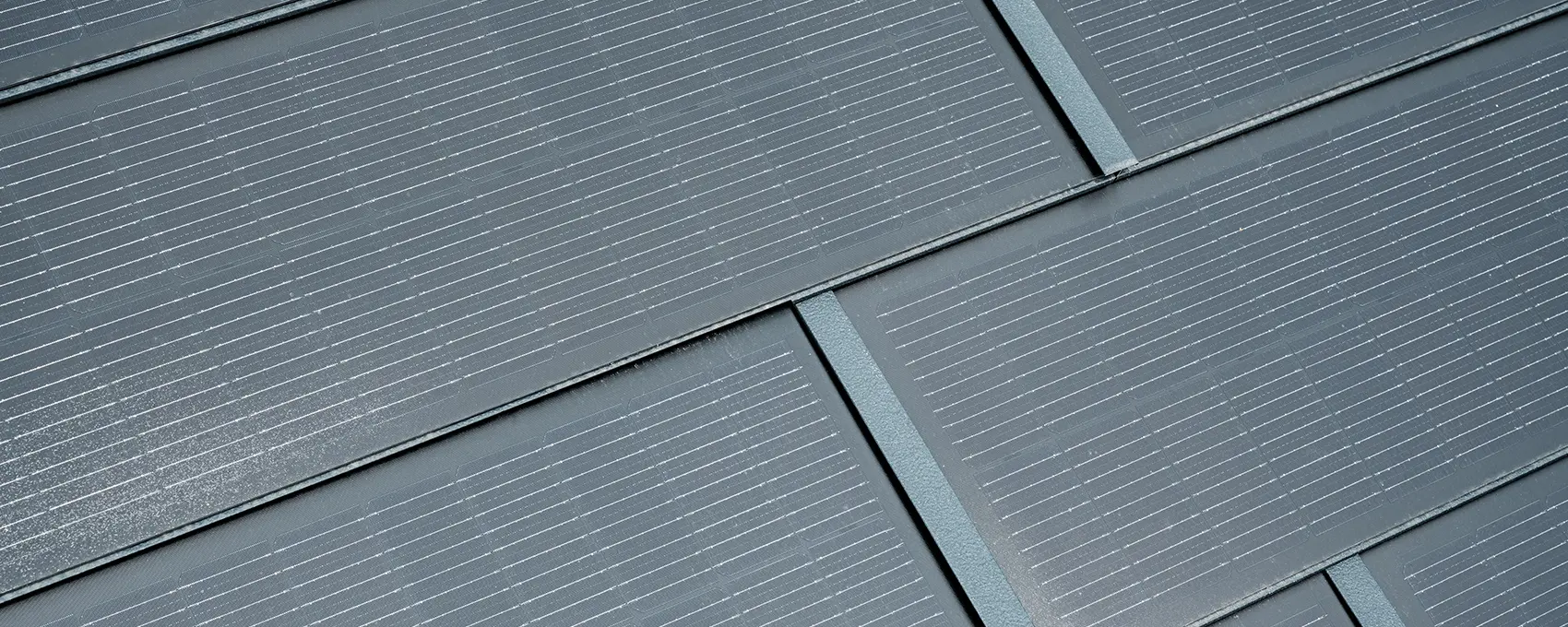 Nærbilde av et montert lite solcelle takplate. Et lite solcelle takplate i fargen P.10 antrasitt ble kombinert med R.16 takplate. 