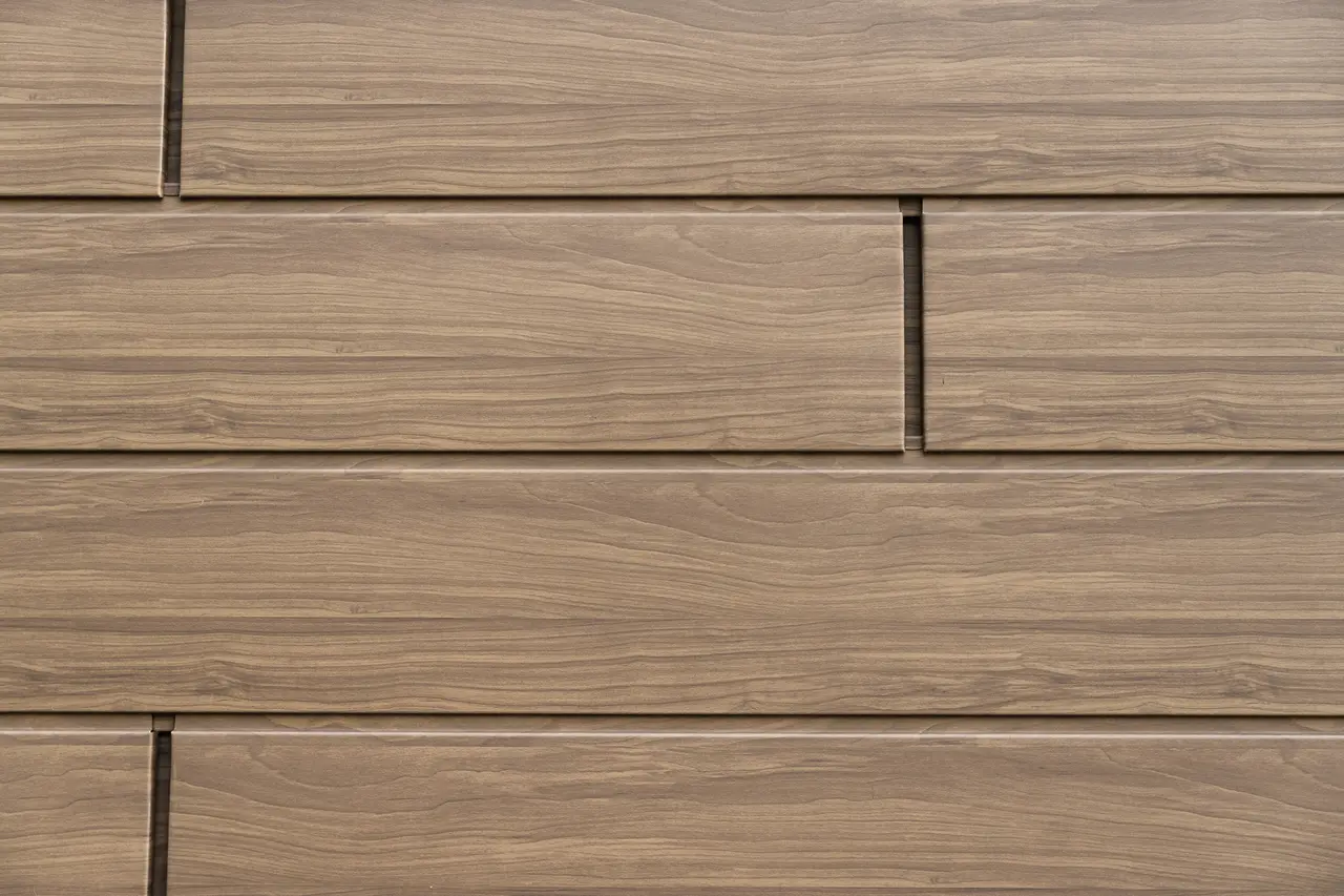 Detailansicht der wallnussbraunen PREFA Sidings mit authentischer Holzoptik. Die langlebigen Aluminium-Fassadenpaneele verbinden natürliche Ästhetik mit Wartungsfreiheit und Witterungsbeständigkeit.