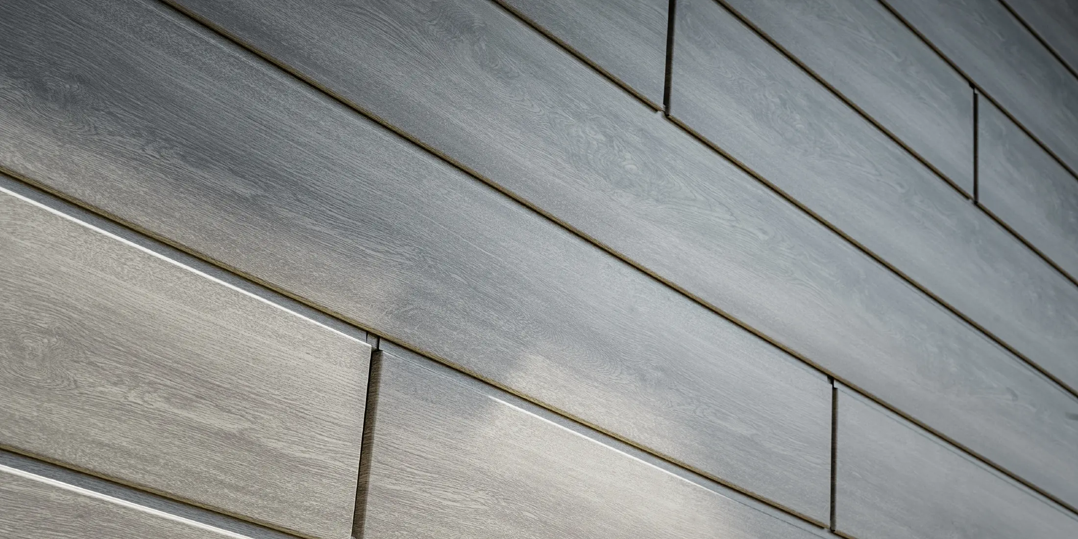 Nærbilde av PREFA Siding aluminiumsfasade, aluminiumsplatene er lagt horisontalt og har treutseende – eik grå.