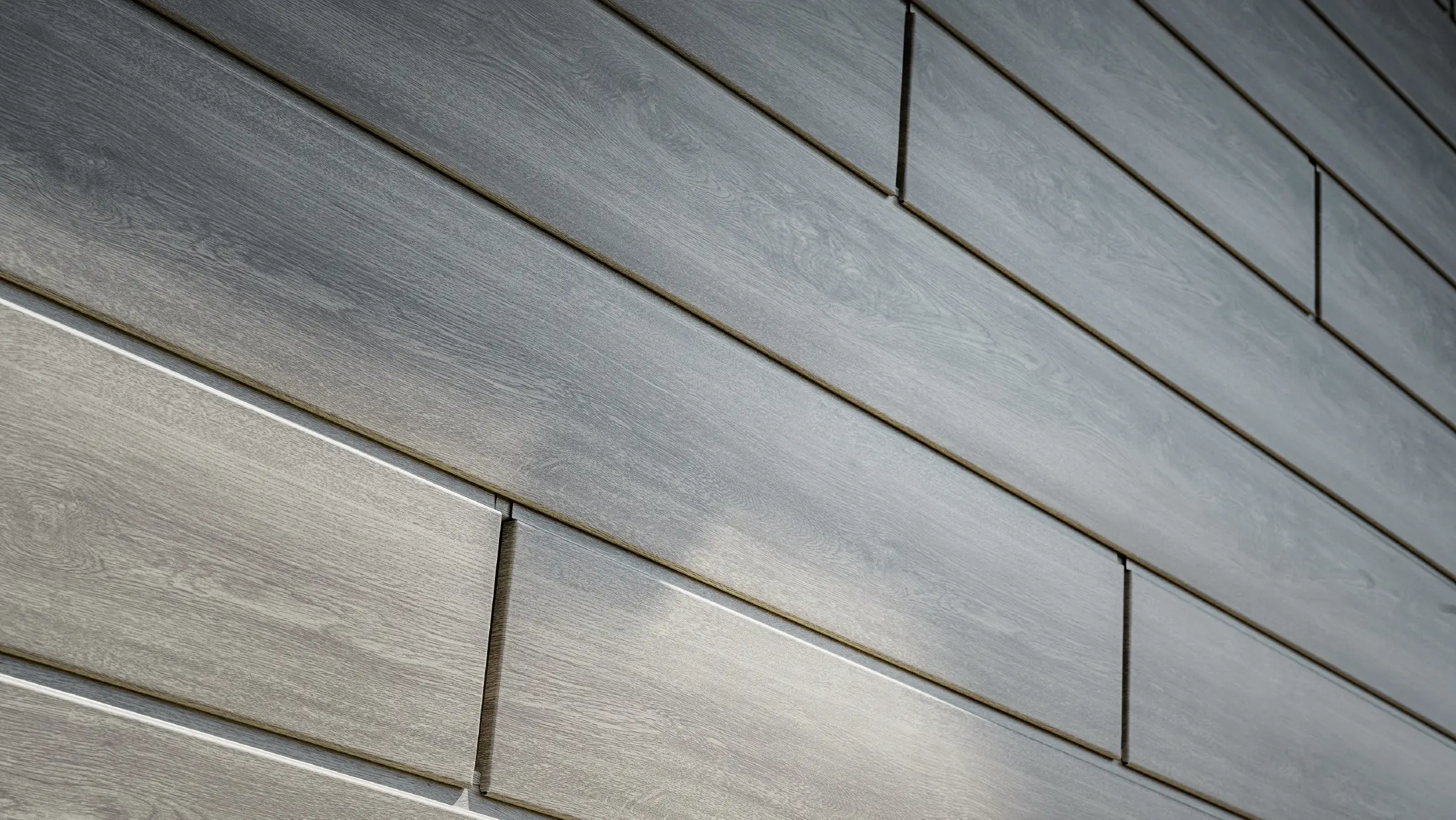 Nærbilde av PREFA Siding aluminiumsfasade, aluminiumsplatene er lagt horisontalt og har treutseende – eik grå.