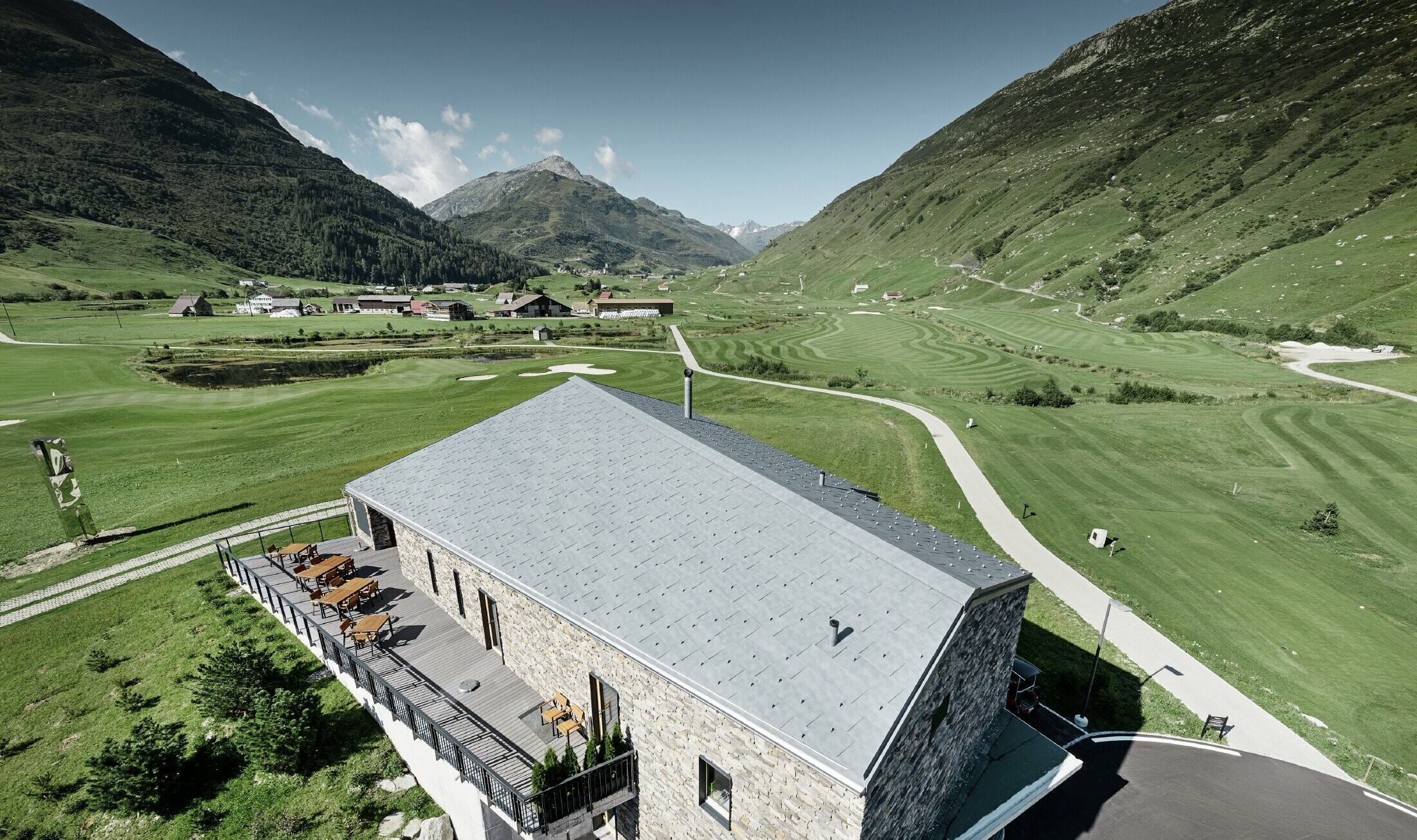 Modernes Club Haus des Golfplatzes in Andermatt mit Steinfassade und PREFA Dachpaneel FX.12 aus Aluminium in steingrau