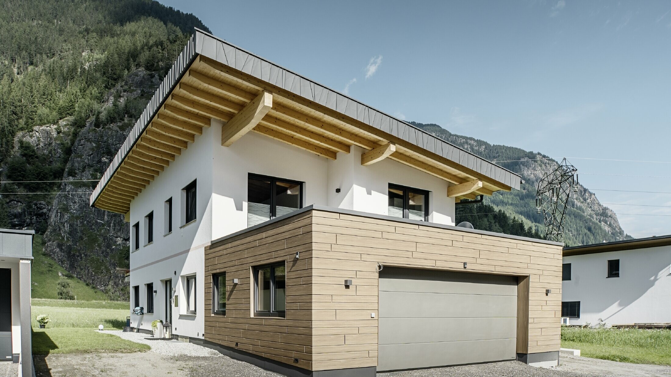 Moderne enebolig med renovert fasade: ny utvendig fasade med horisontal fasadekledning i treutseende, kombinert med hvitpussede flater, integrert garasjekledning og moderne arkitektur i alpint miljø.
