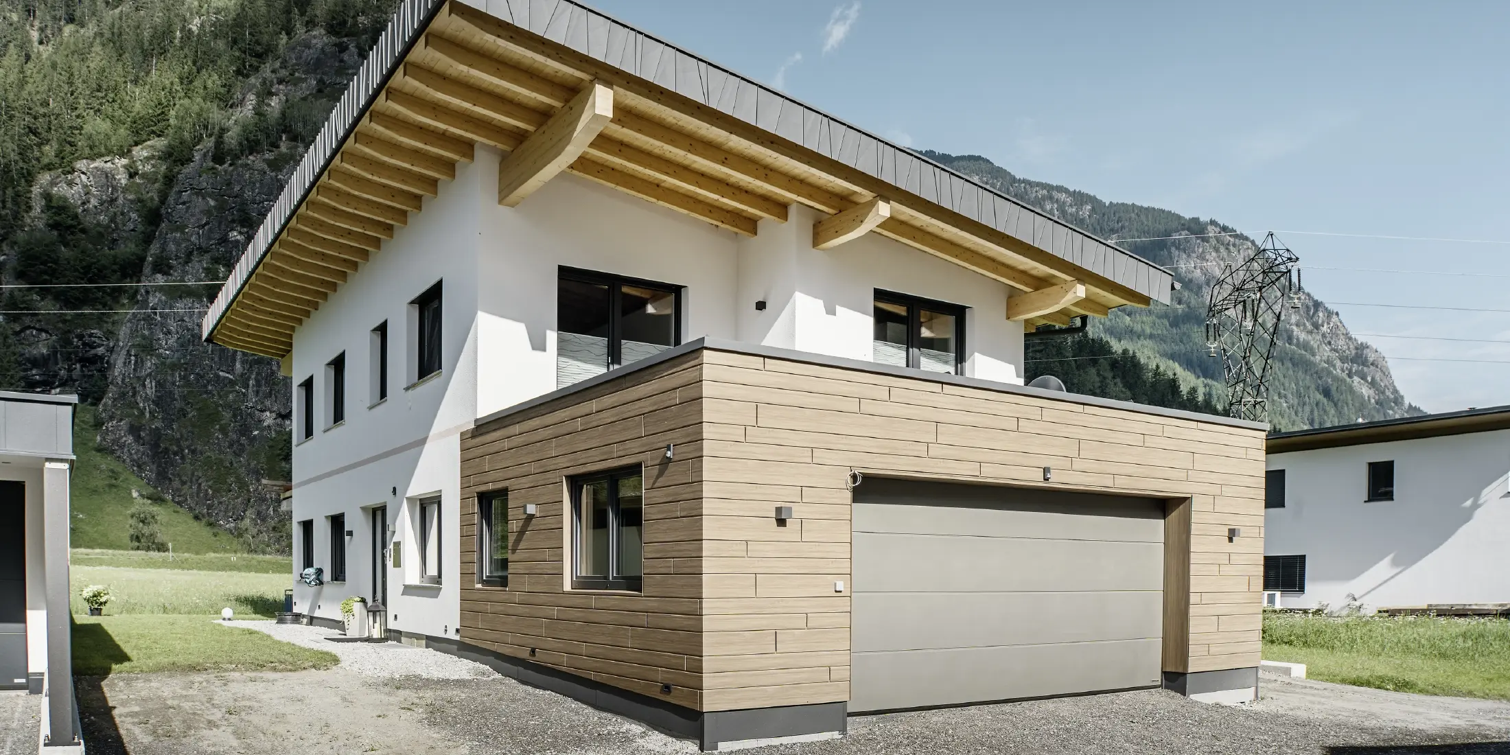 Moderne enebolig med renovert fasade: ny utvendig fasade med horisontal fasadekledning i treutseende, kombinert med hvitpussede flater, integrert garasjekledning og moderne arkitektur i alpint miljø.