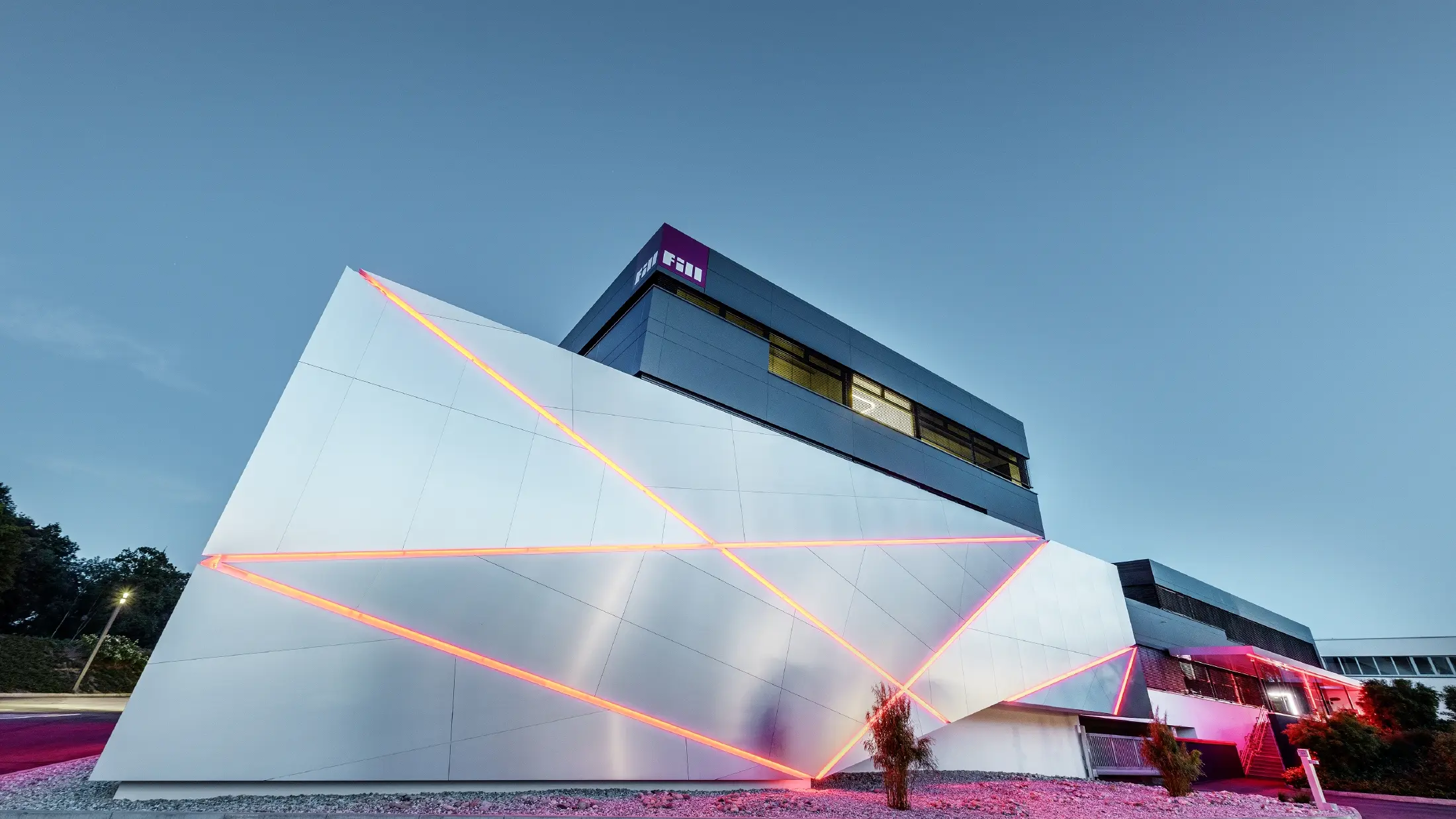 Fill-firmas bygning med futuristisk fasade av aluminiumsplater i børstet aluminium og bakgrunnsbelyste fuger.