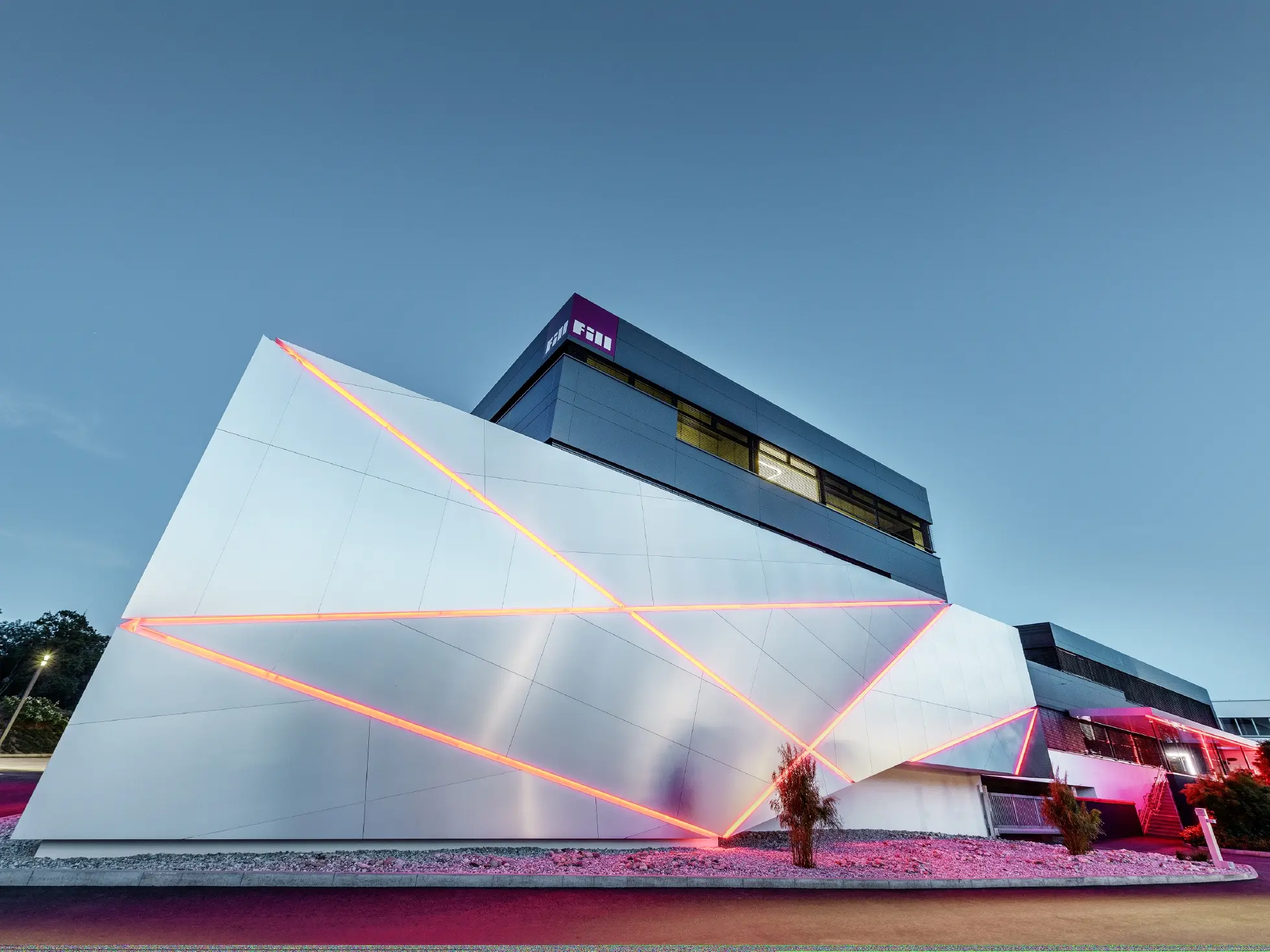 Fill-firmas bygning med futuristisk fasade av aluminiumsplater i børstet aluminium og bakgrunnsbelyste fuger.