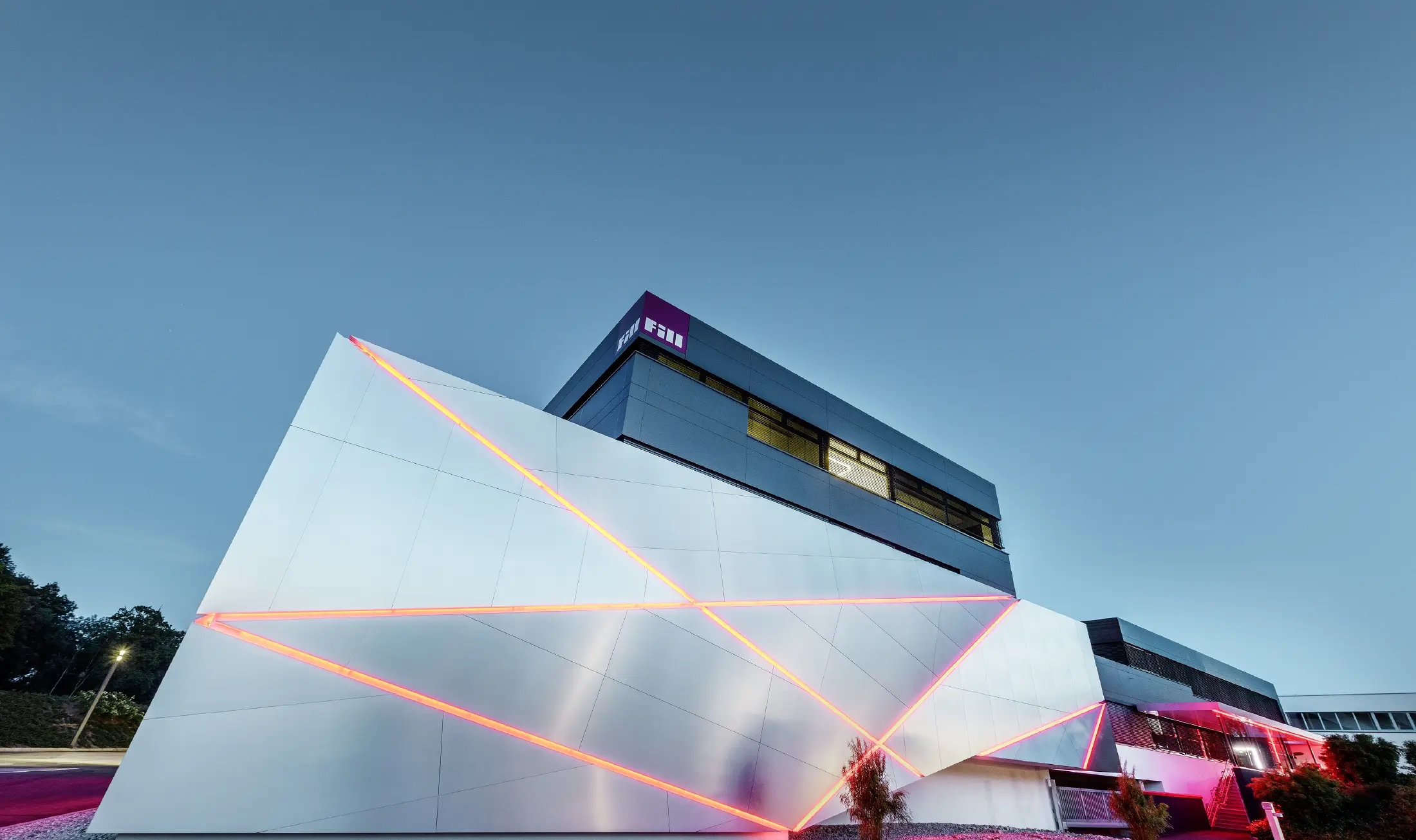 Fill-firmas bygning med futuristisk fasade av aluminiumsplater i børstet aluminium og bakgrunnsbelyste fuger.