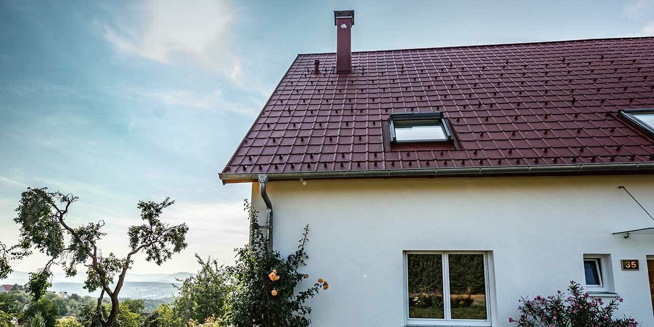 Hus på landet, nyrenovert tak med PREFA takplate i oksydrød, takvindu og pipekledning.