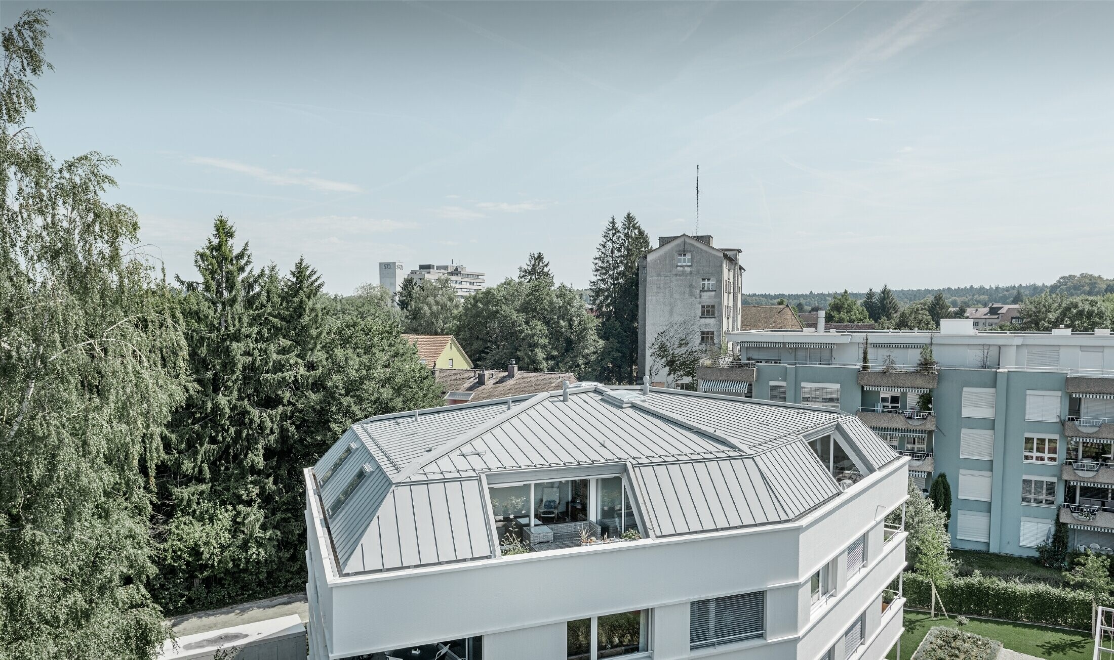 Taket på et appartementshus kledd med PREFA Prefalz i patinagrå med overbygd gang.