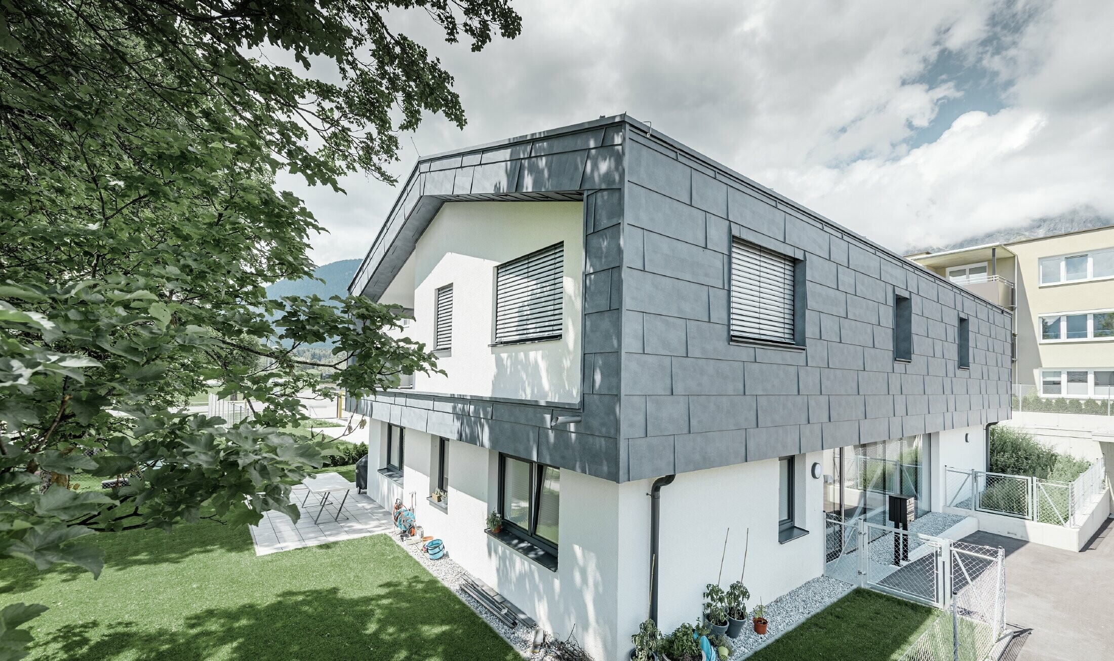 Moderne tilbygg på et bolighus med flatt saltak og uten takfremspring.  Fasadekledningen er utført med PREFA fasadepanel FX.12 i steingrå.