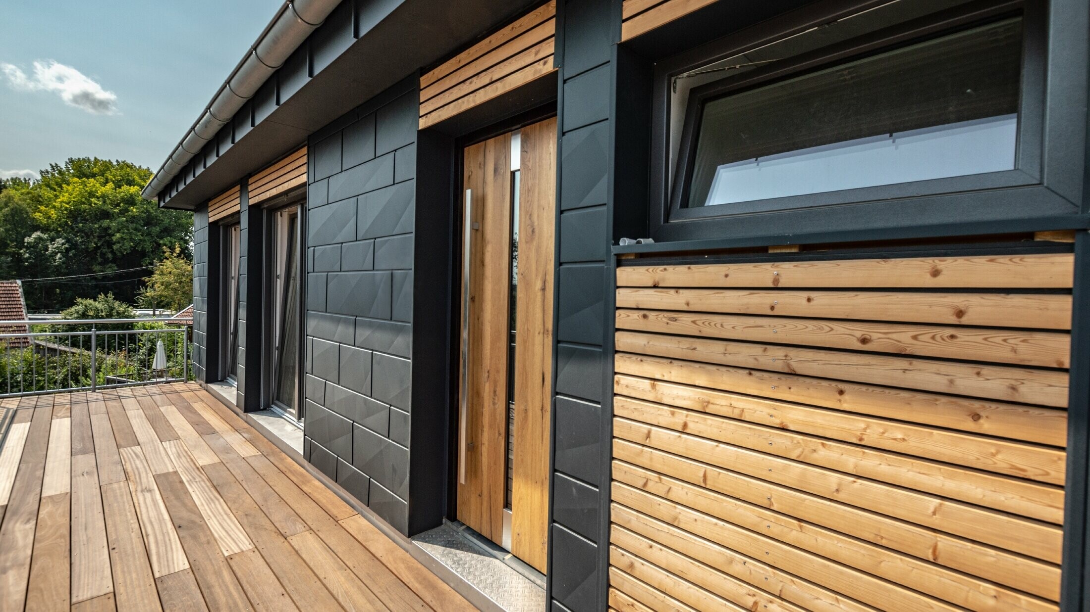 Fasadeutforming ved å blande materialer aluminium – PREFA Siding.X i antrasitt – og horisontale trelister.
