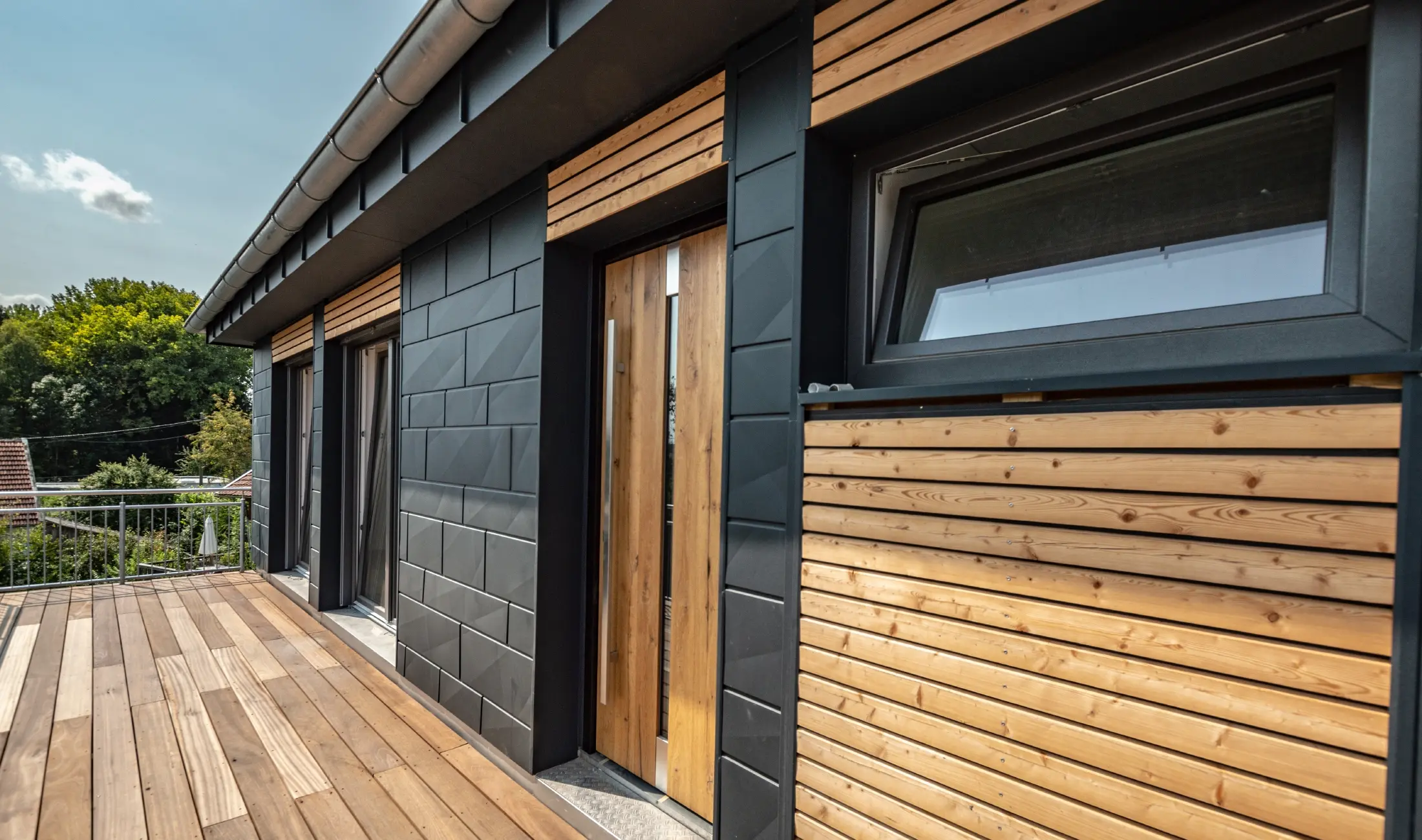 Fasadeutforming ved å blande materialer aluminium – PREFA Siding.X i antrasitt – og horisontale trelister.