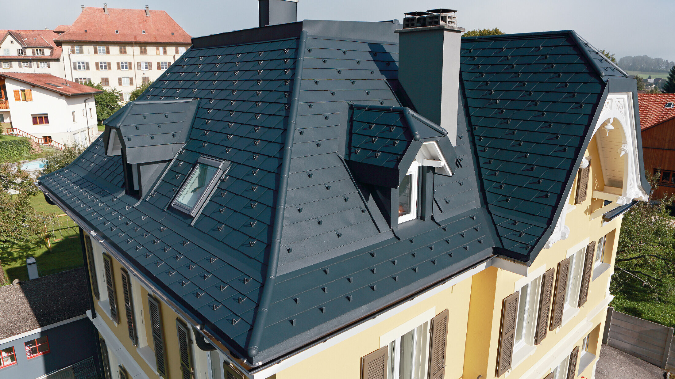 Villa i Sveits, taket har mange vinkelrenner og små arker, taket er dekket med aluminiumsshingel fra PREFA i P.10 antrasitt