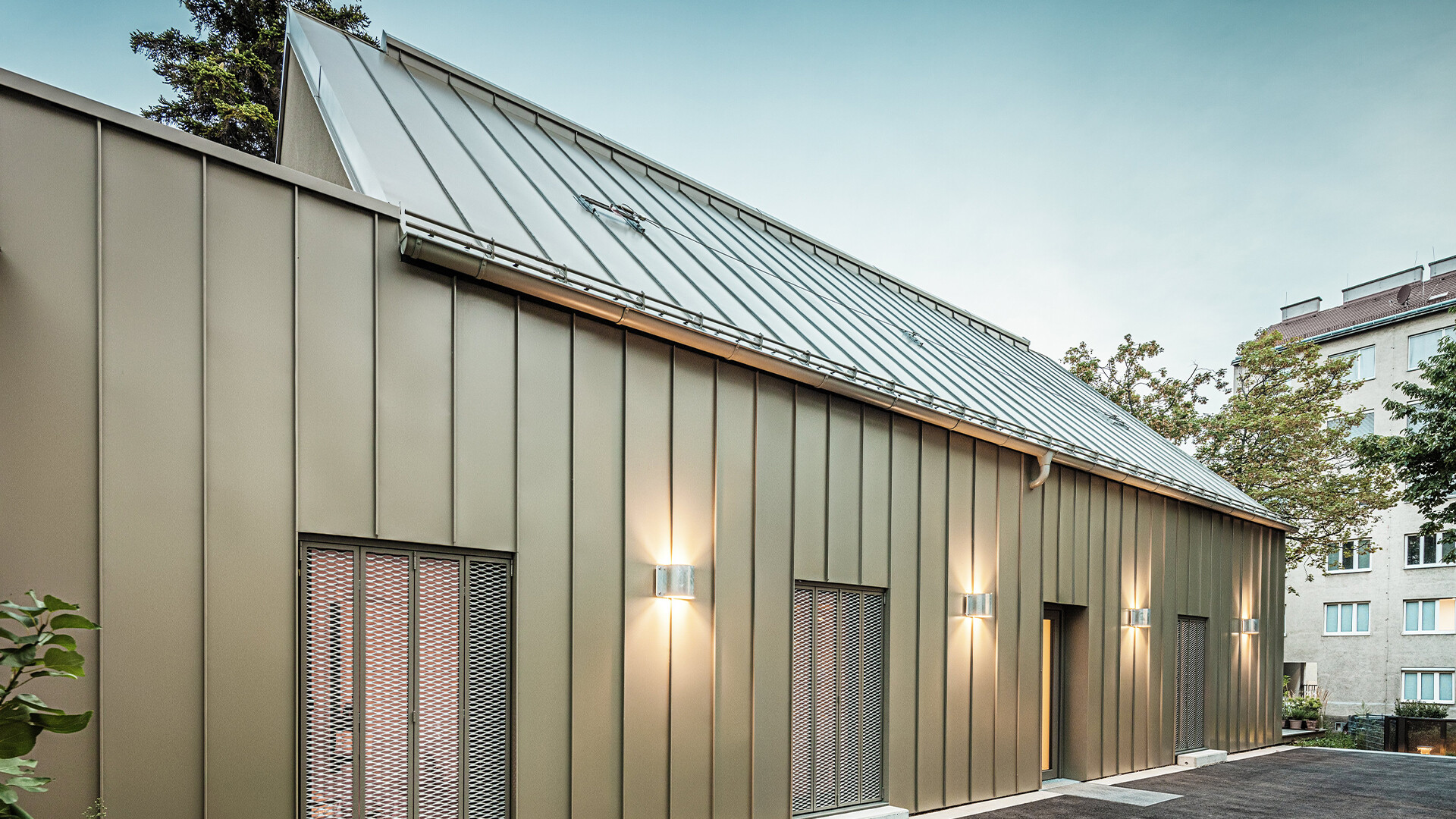 Bildet viser et nærbilde av Atelier Comploj med fasade og tak i PREFALZ i fargen P.10 Prefabronse.