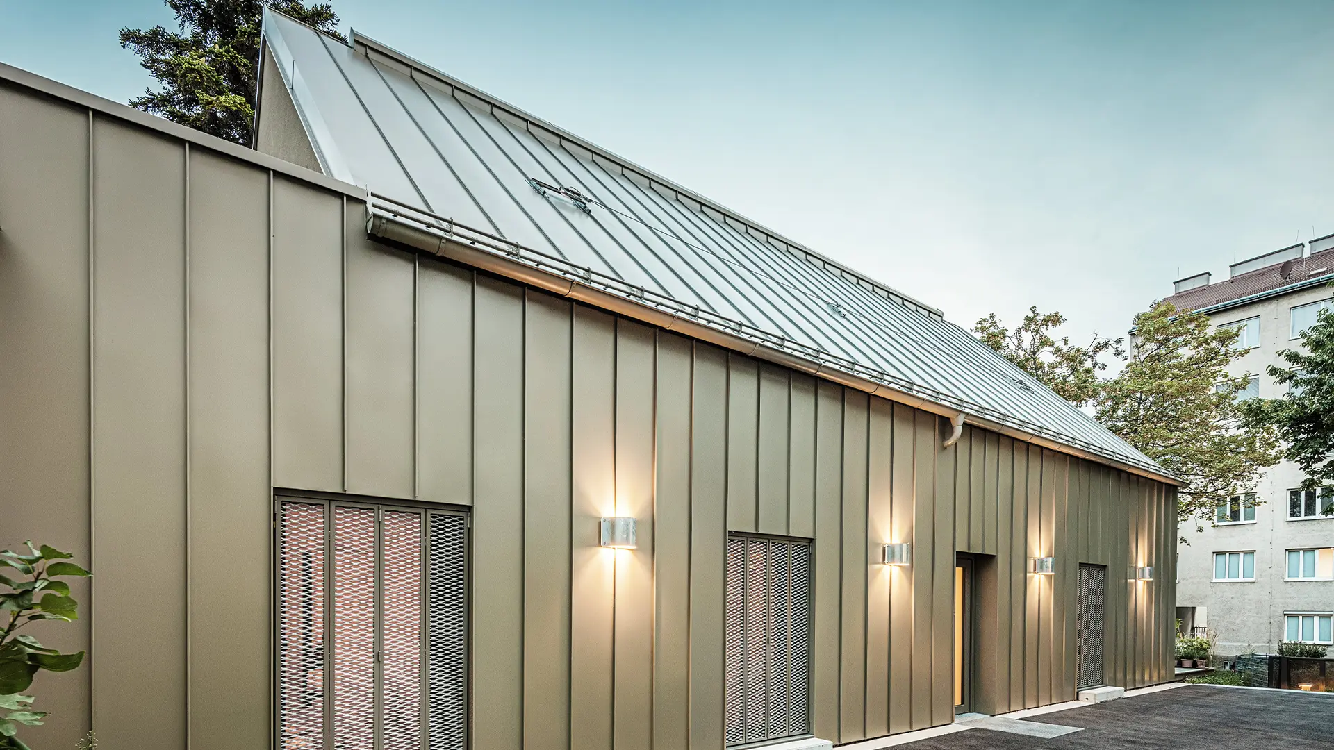 Bildet viser et nærbilde av Atelier Comploj med fasade og tak i PREFALZ i fargen P.10 Prefabronse.