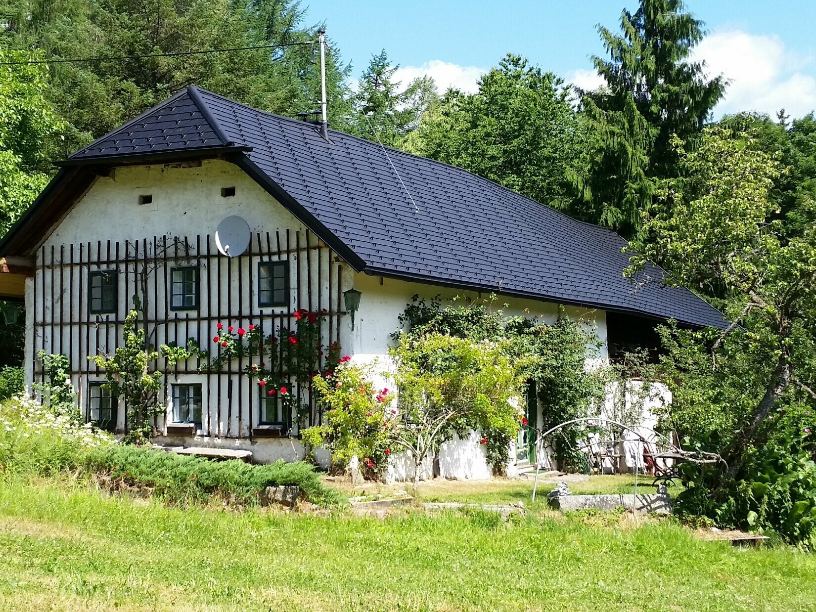 Dette billede viser et gammelt bondehus, efter at taget er blevet renoveret. Taget på det såkaldte enghus er dækket med PREFA tagshingles P.10 sort. 