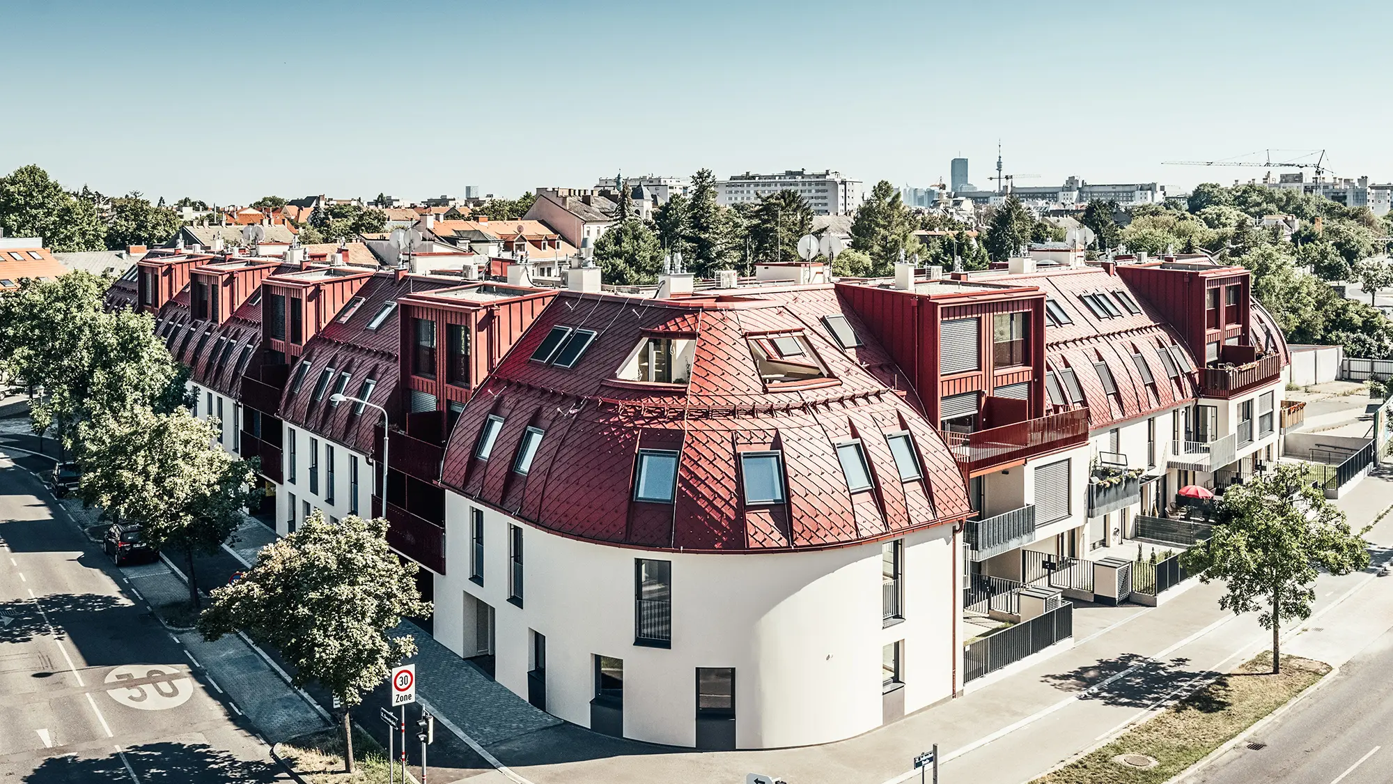 Straßenansicht auf die Wohnanlage Schöneck 13 und die abgerundete Dachlandschaft, entworfen vom Architekturbüro schneider+schumacher.