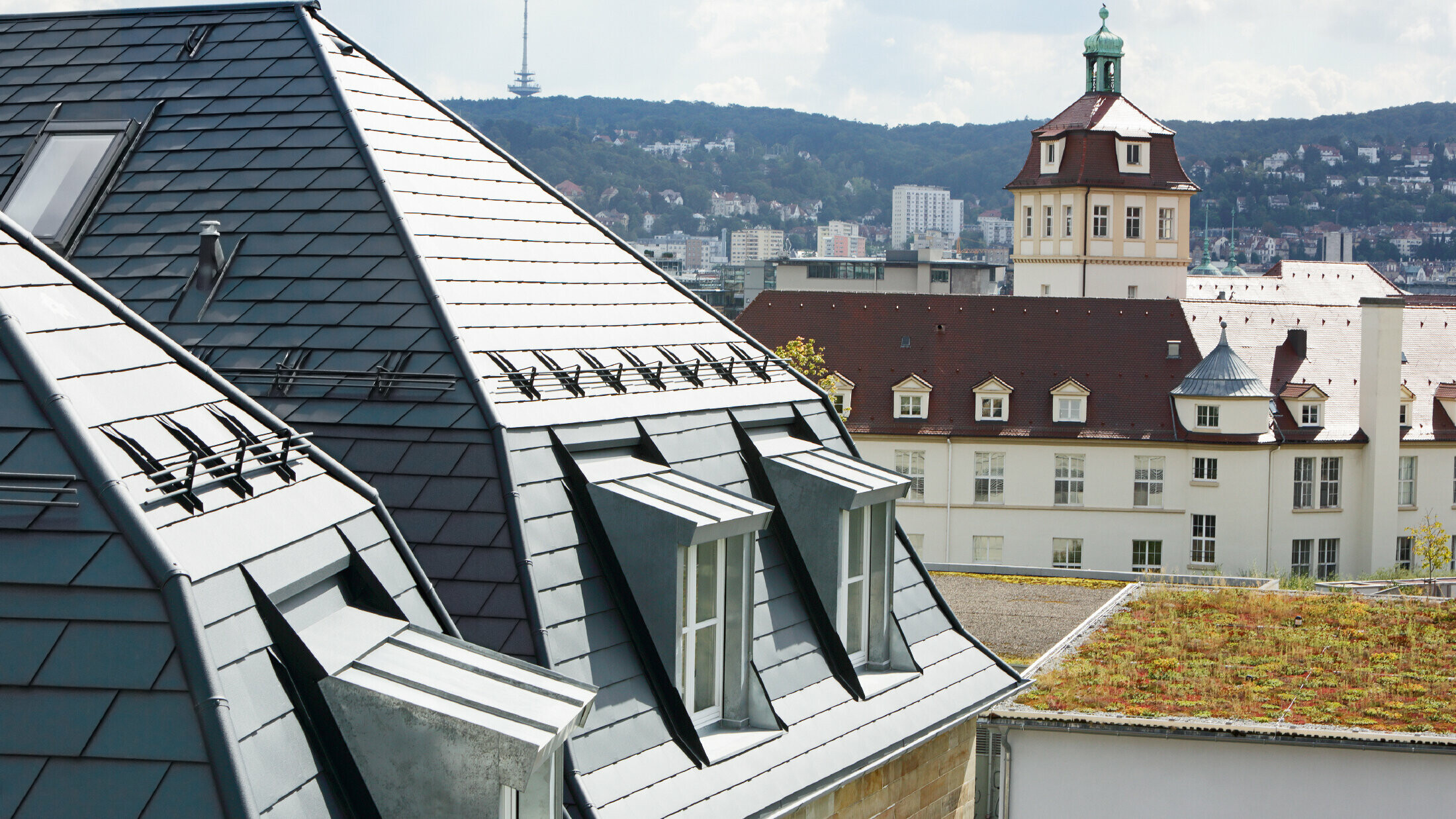 Gammelt rekkehus i Stuttgart med skjevt tak og mange arkvinduer, dekket med aluminiumsshingel fra PREFA i P.10 antrasitt