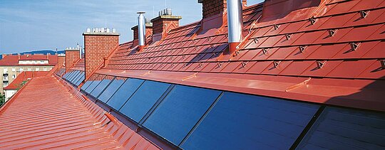 Detaljbilde av PREFA-takshingel i mursteinsrød inkludert snøstoppere ved Hugo Breitner Hof.