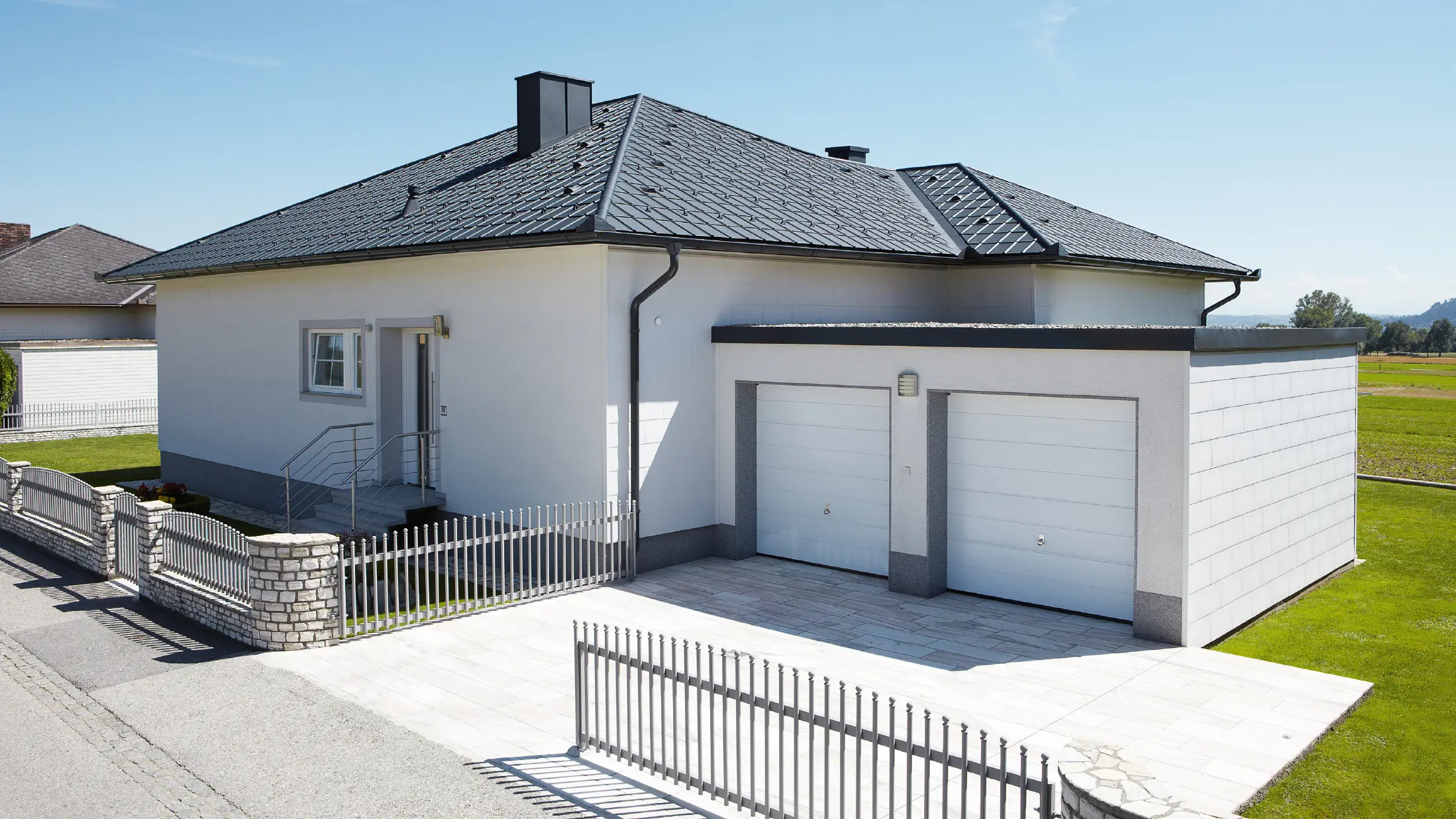 Den nybygde bungalowen med telttak ble dekket med PREFA takplate i P.10 antrasitt. Til høyre, fotografert fra gaten, ble det bygget en dobbeltgarasje.