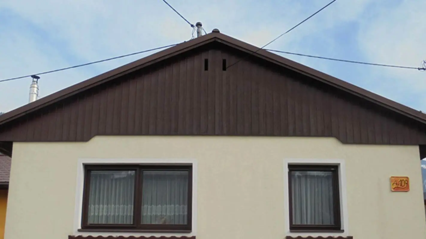 Før renovering av fasaden på gavlen med PREFA Sidings, gul pussfasade og forvitret tre