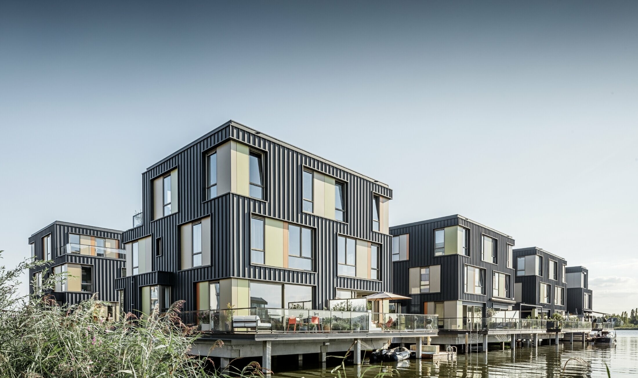 Ny boligpark med tomannsboliger ved en innsjø i Amsterdam. Husene er kledd med Prefalz fra PREFA i P.10 antrasitt.