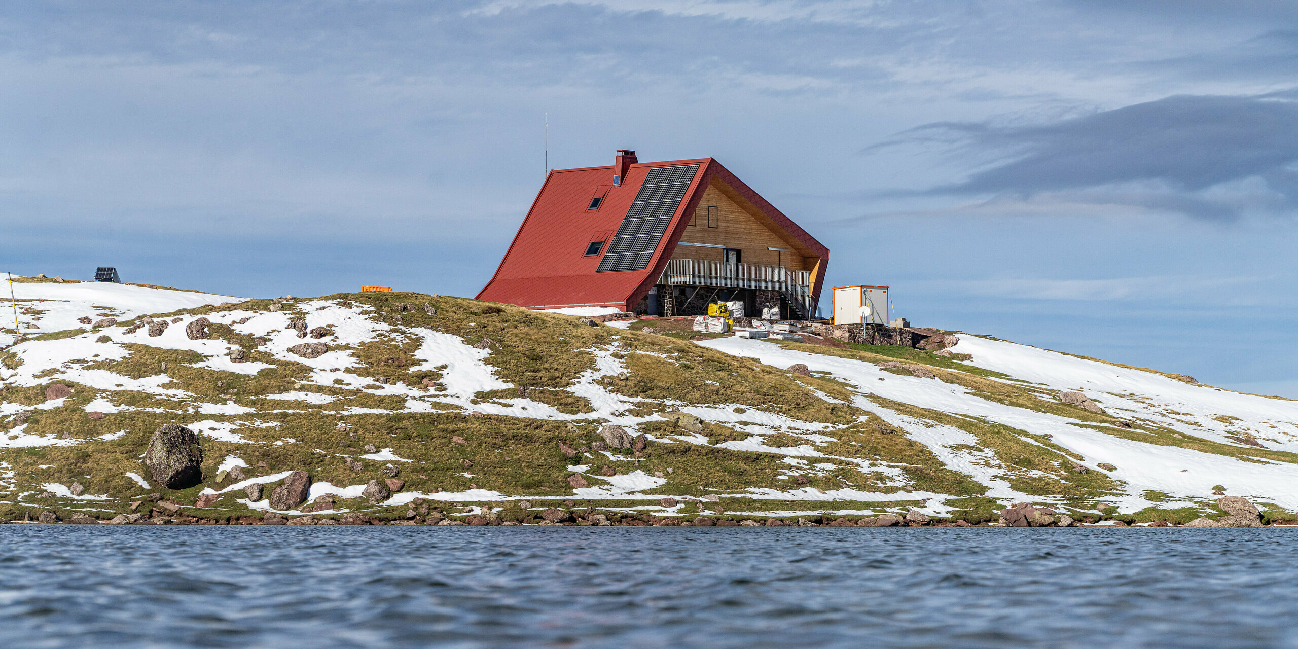 Der See vor der Schutzhütte Arlet im Pyrenäen-Nationalpark liegt im Vordergrund des Bildes. Das Gebäude mit der oxydroten Aluminiumhülle ist nur aus der Distanz zu sehen. 