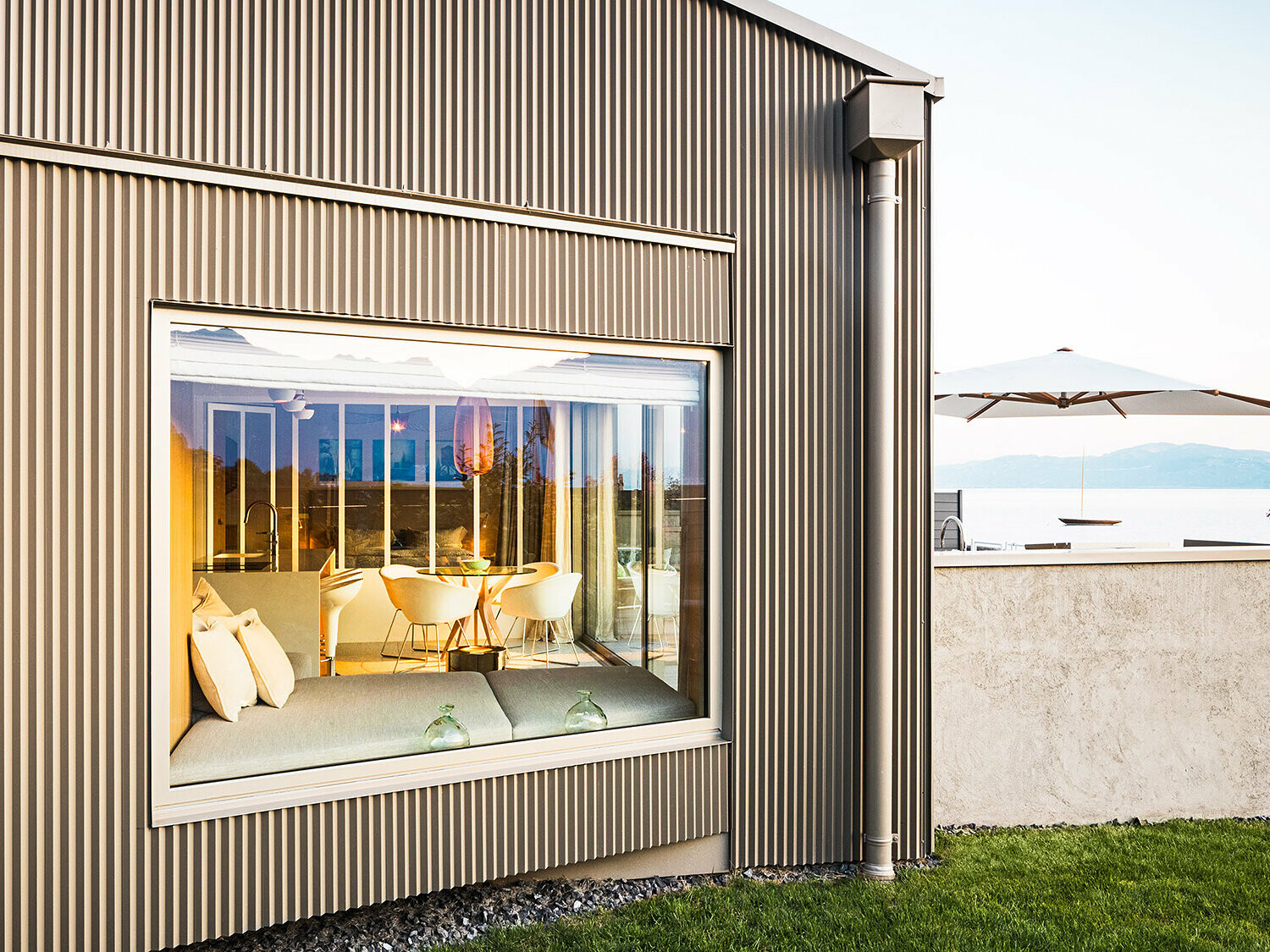 Sidevisning av bygningen med sikksakkformet aluminiumfasade, der deler av det belyste interiøret er synlig.