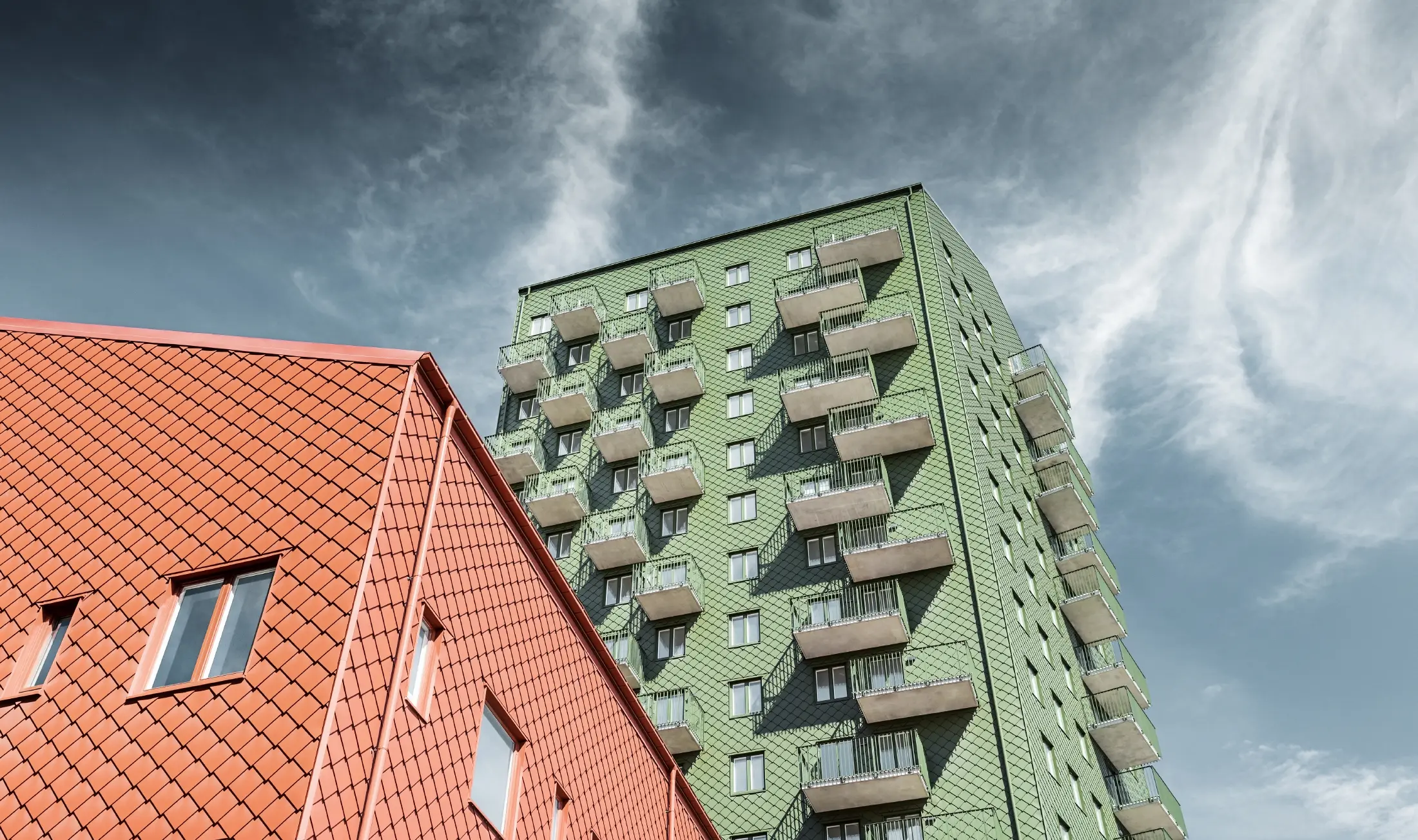 Høyhus med balkonger med fasadeutforming med PREFA veggrombe 29 × 29 i olivengrønt og teglrødt
