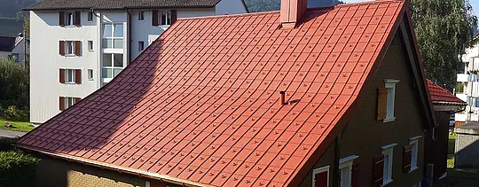 Saltak dekket med PREFA-takplate i aluminium. Tak i mursteinsrødt med snøstoppere og kamin