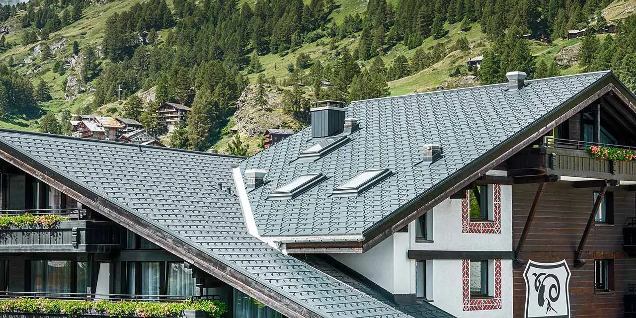 Hotelalpenhof in Zermatt mit dem Matterhorn im Hintergund, Balkonen, dunkler Holzfassade und einem PREFA Aluminiumdach in anthrazit